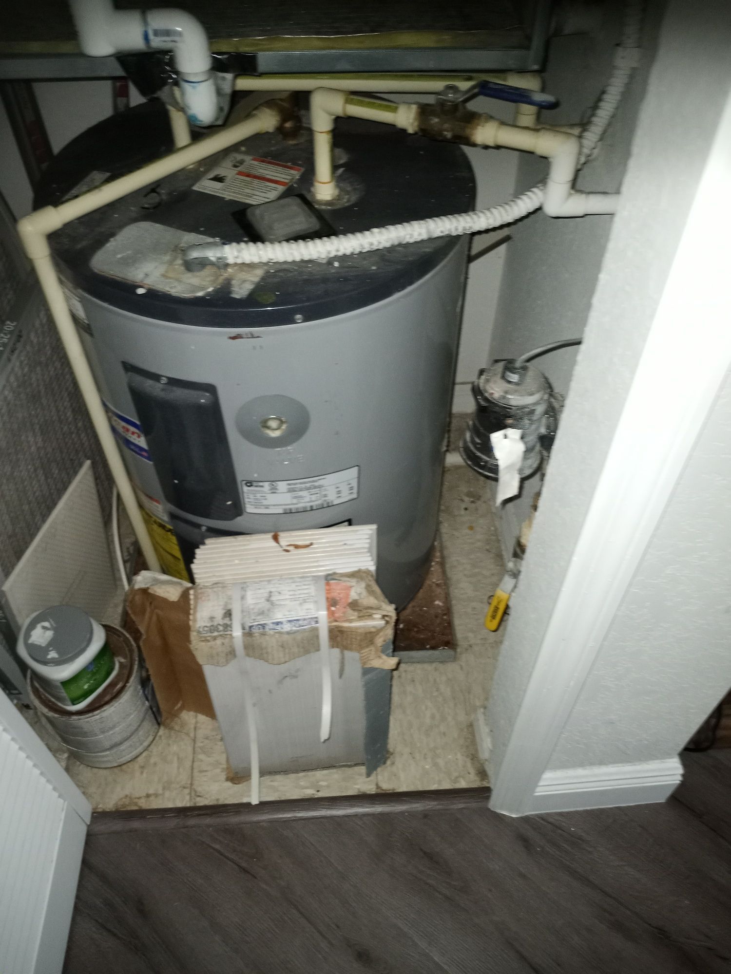 a water heater is sitting in a corner of a room .