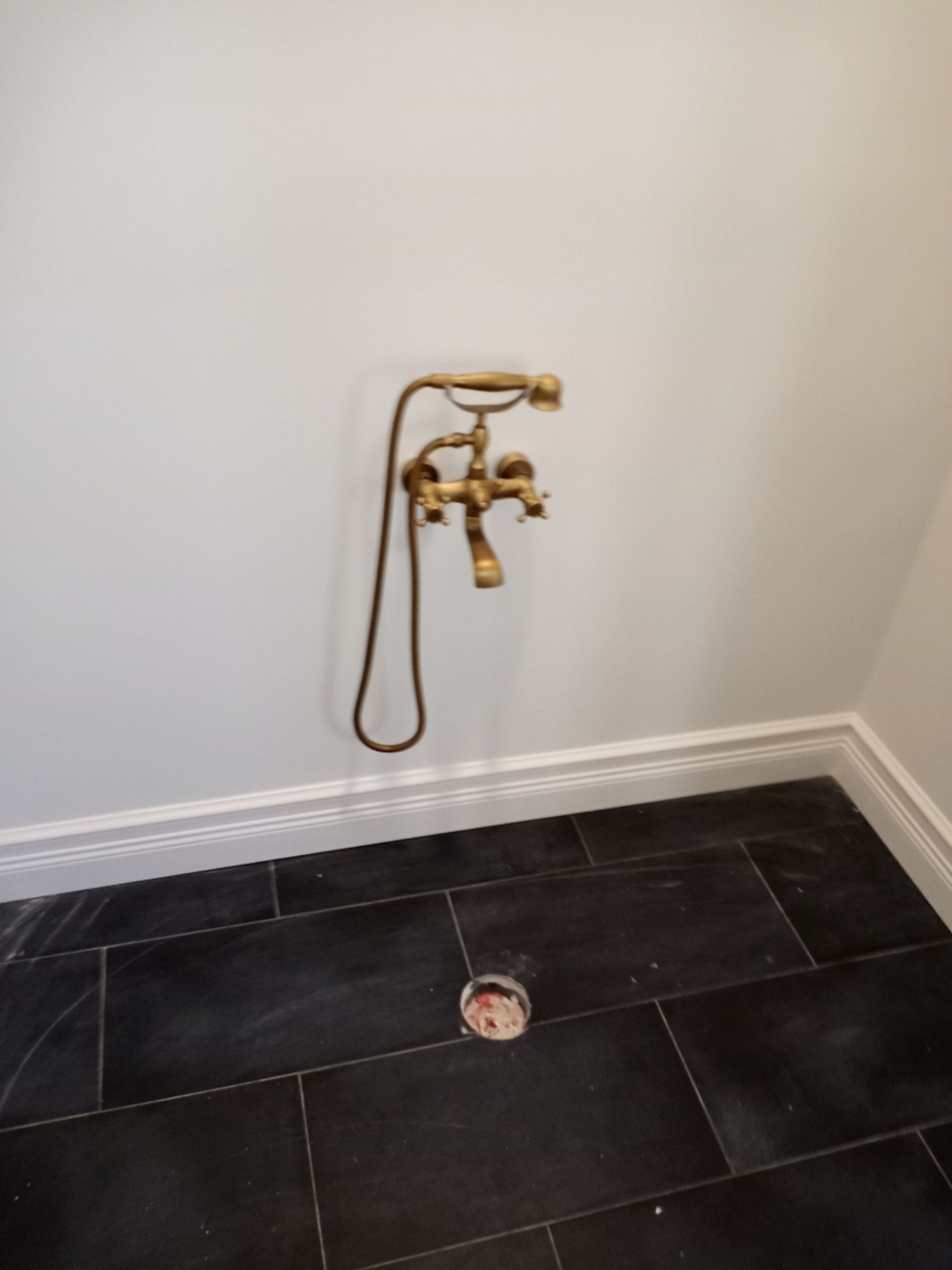 a brass shower head is hanging from the wall in a bathroom .