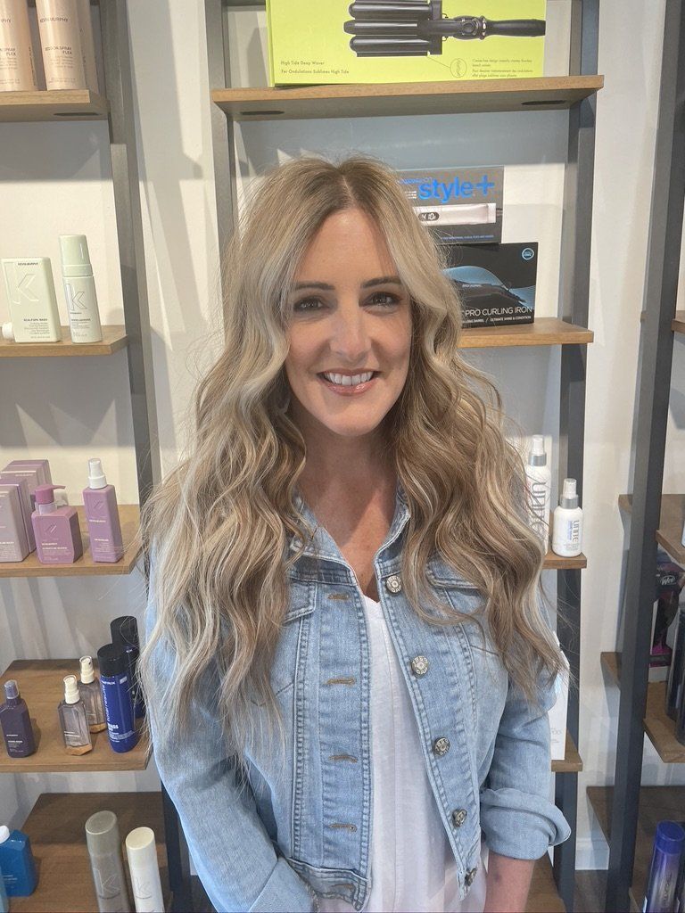 A woman in a denim jacket is standing in front of a shelf filled with hair products.