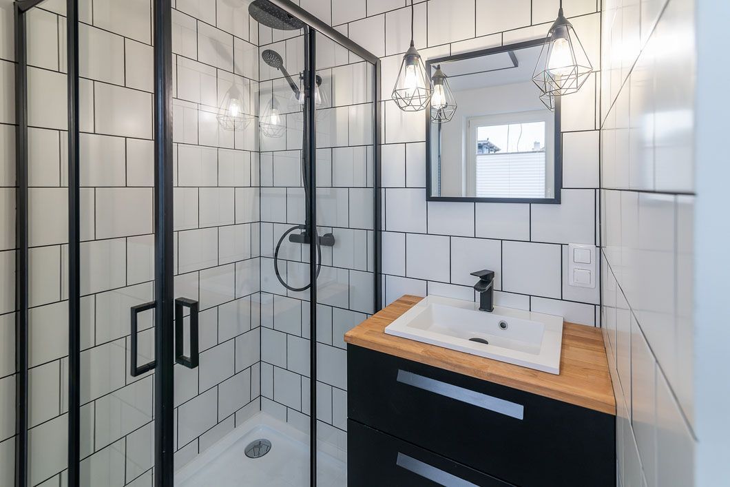 A bathroom with a sink , shower , and mirror.