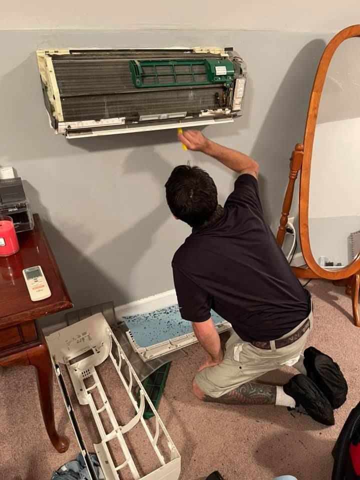 A man is cleaning an air conditioner in a room