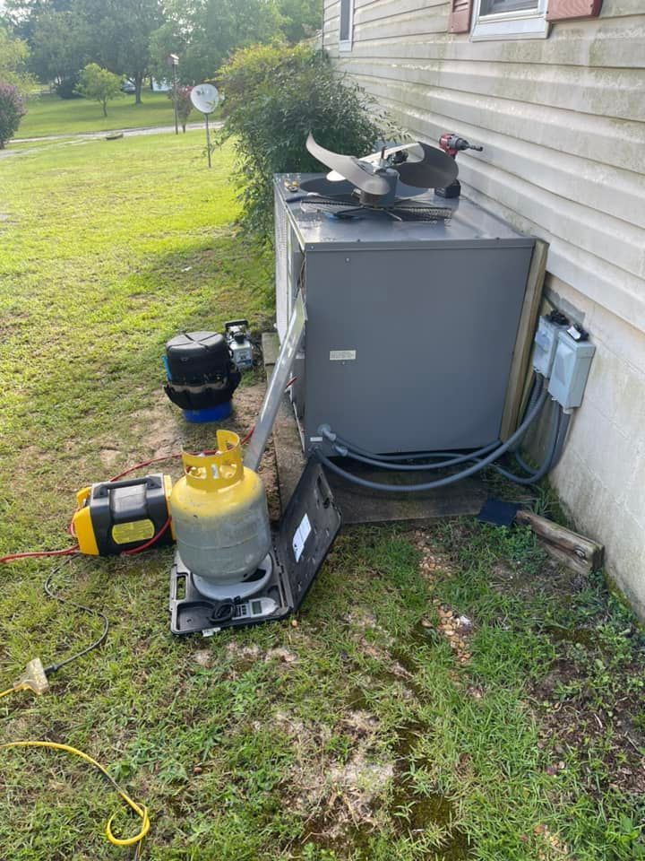 An air conditioner is sitting in the grass next to a house .