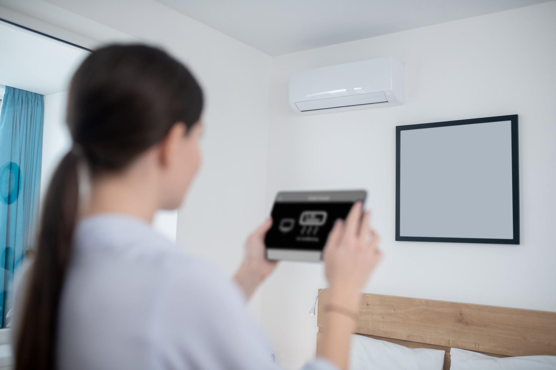 a woman is holding a tablet in her hand in a bedroom .