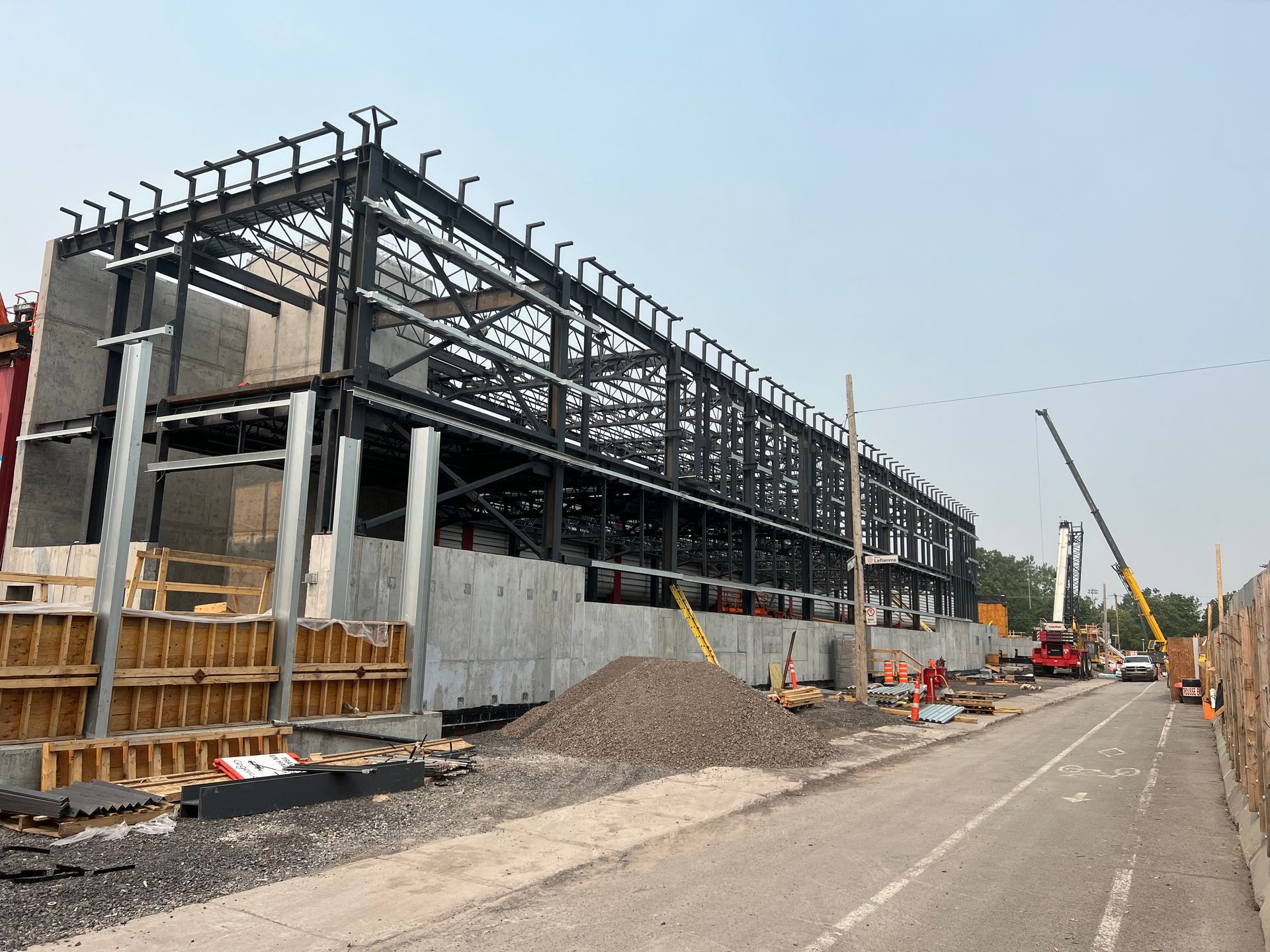 Un grand bâtiment est en construction à côté d'une route.