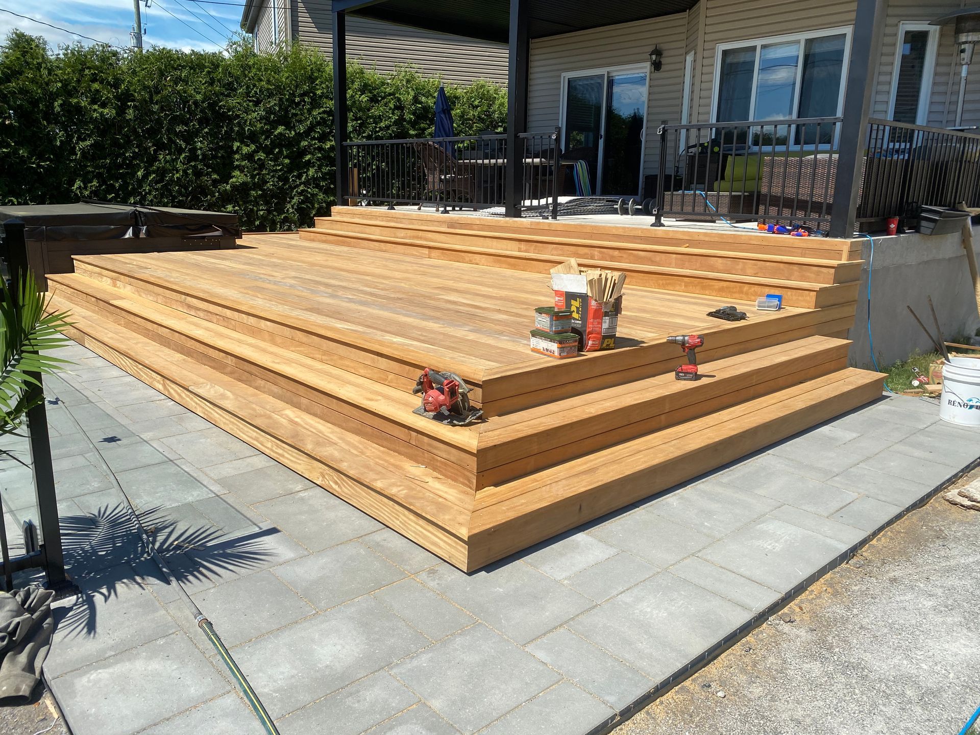 Une terrasse en bois avec des escaliers est en cours de construction devant une maison.