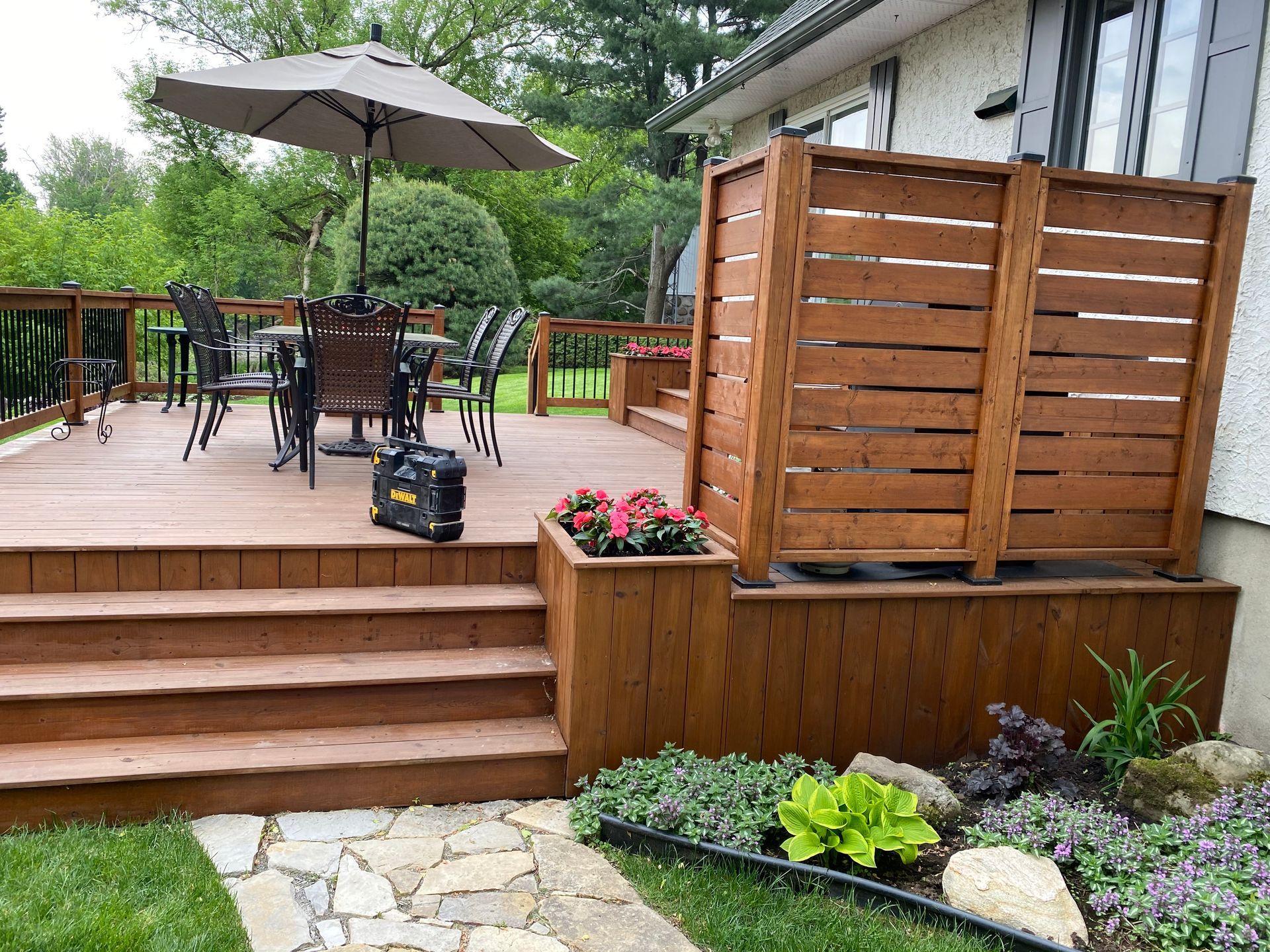 Une terrasse en bois avec une table, des chaises et un parasol.