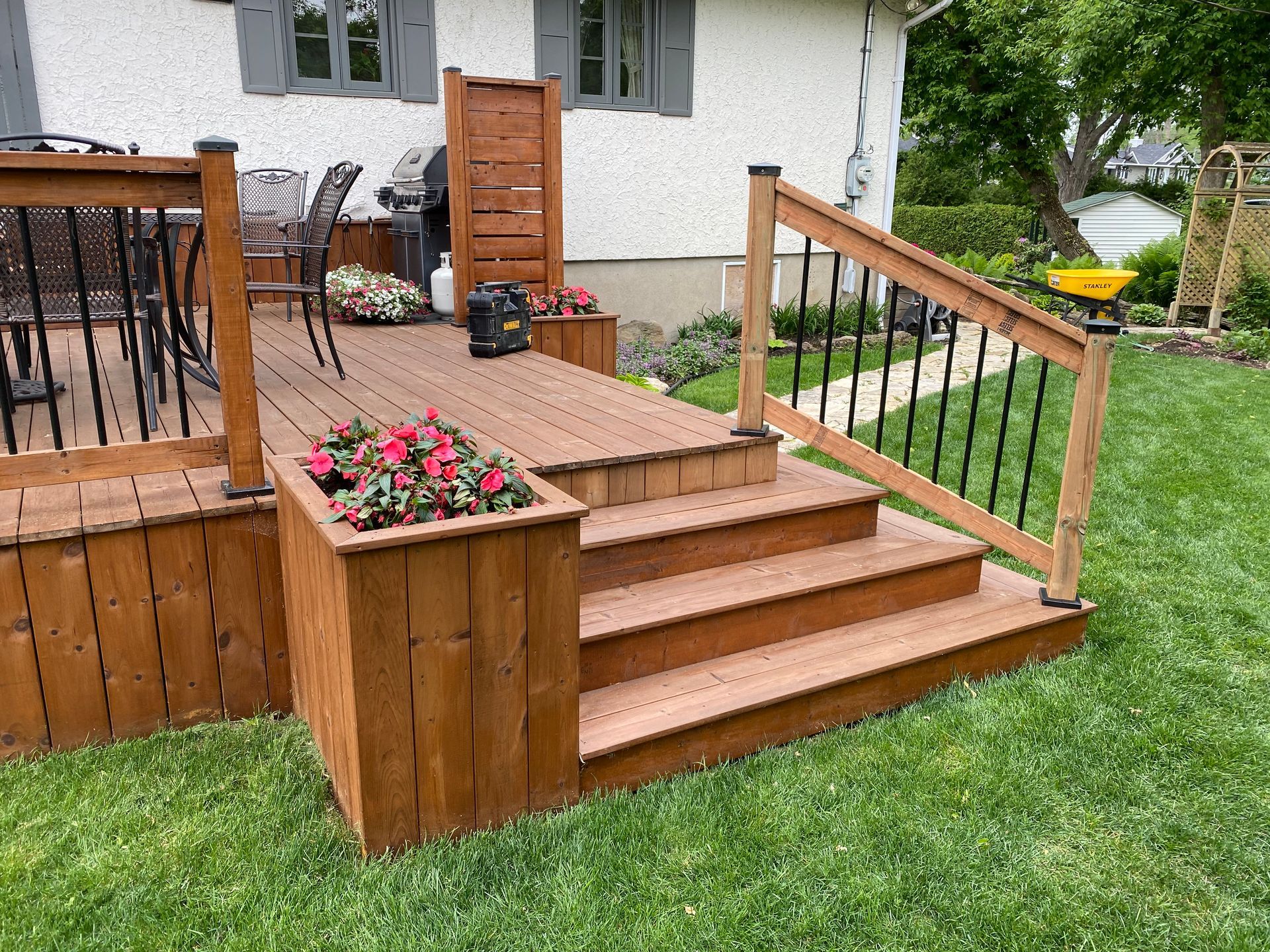 Une terrasse en bois avec des escaliers qui y mènent se trouve dans l'arrière-cour d'une maison.