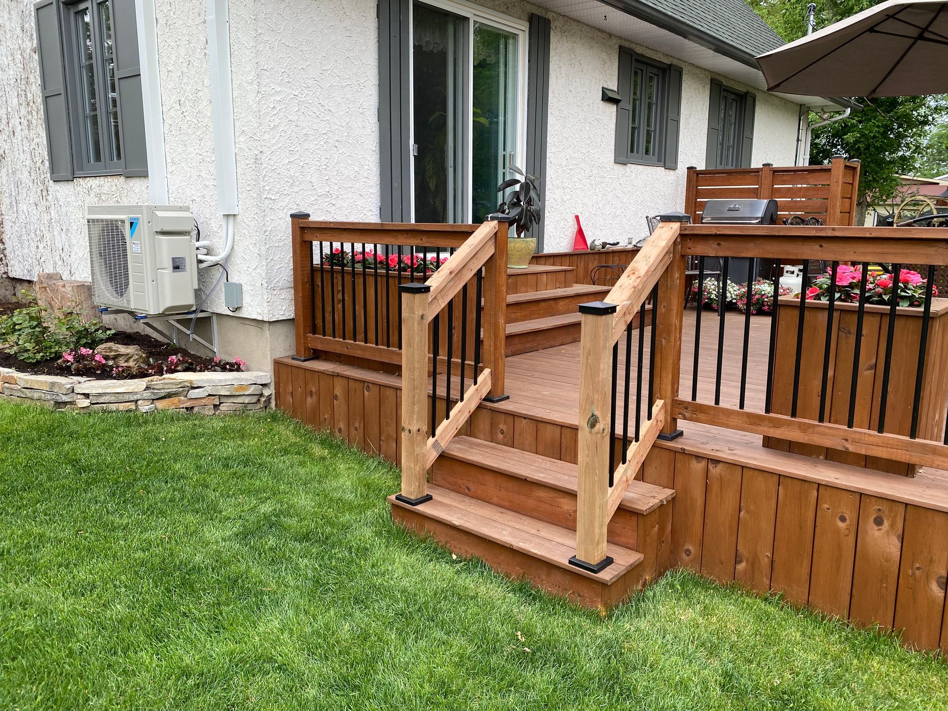 Une terrasse en bois avec des escaliers qui y mènent se trouve dans l'arrière-cour d'une maison.