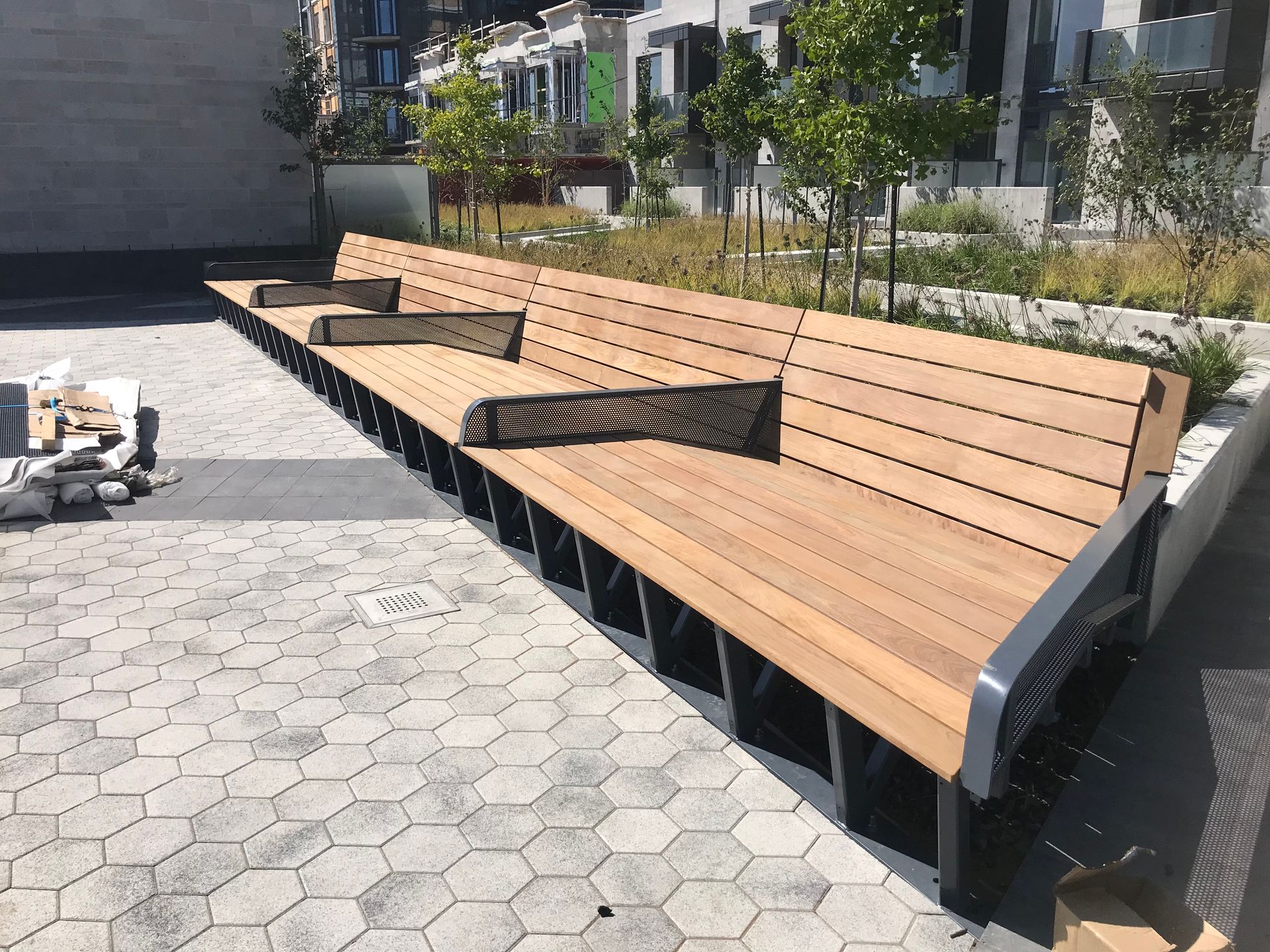 Une rangée de bancs en bois est posée sur un trottoir en briques.