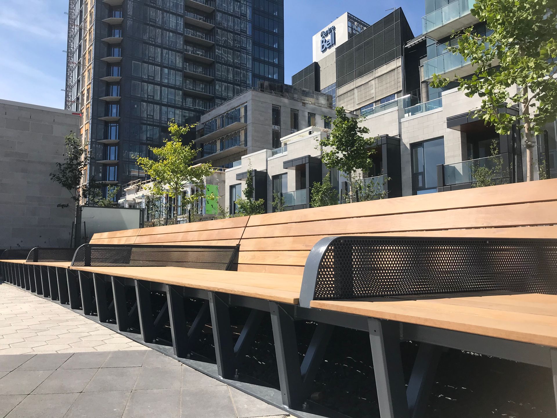 Une rangée de bancs en bois sur un trottoir devant un bâtiment.