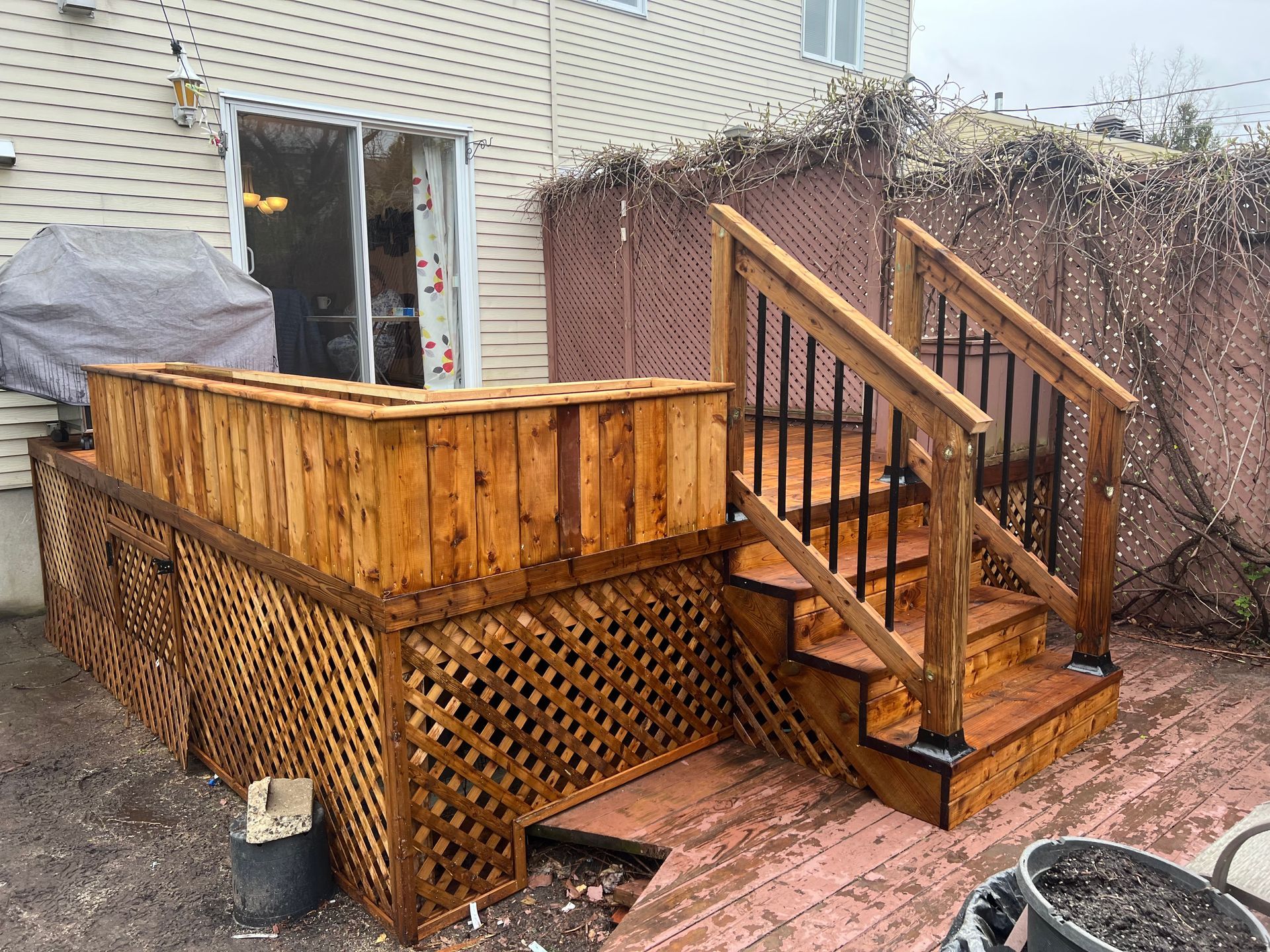 Une terrasse en bois avec des escaliers et un barbecue dans l'arrière-cour d'une maison.