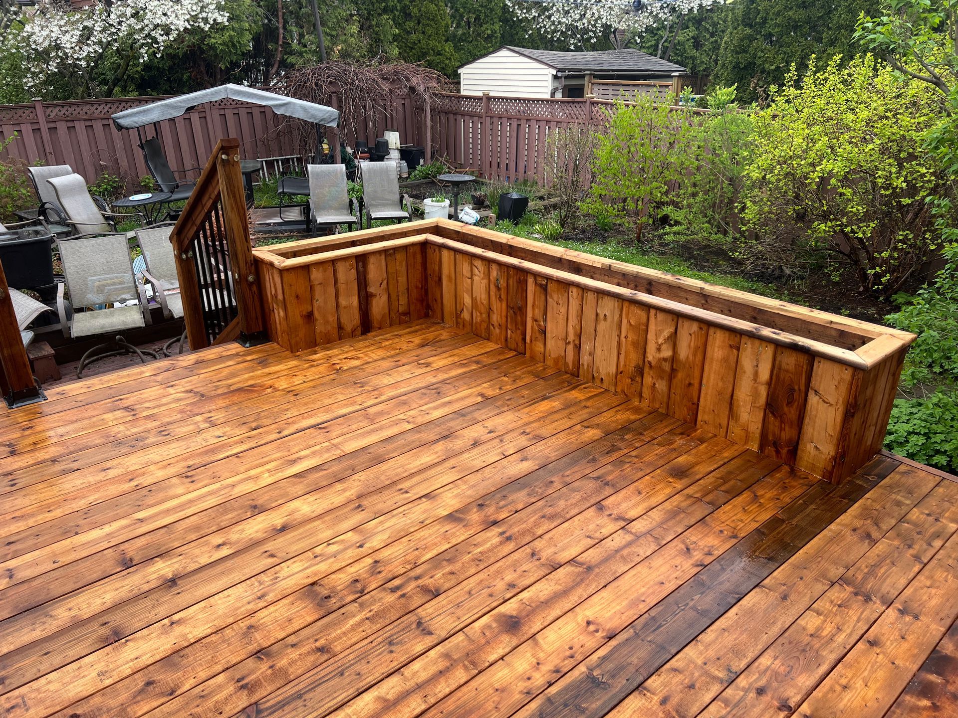 Une terrasse en bois avec une jardinière au milieu.
