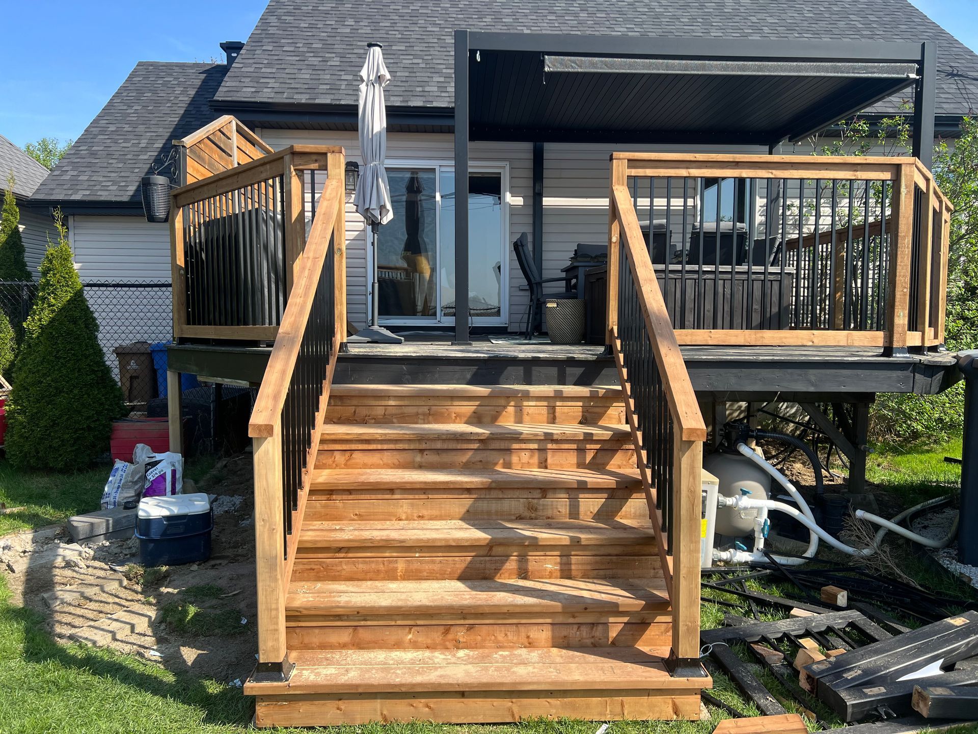 Une terrasse en bois avec des escaliers qui y mènent se trouve devant une maison.