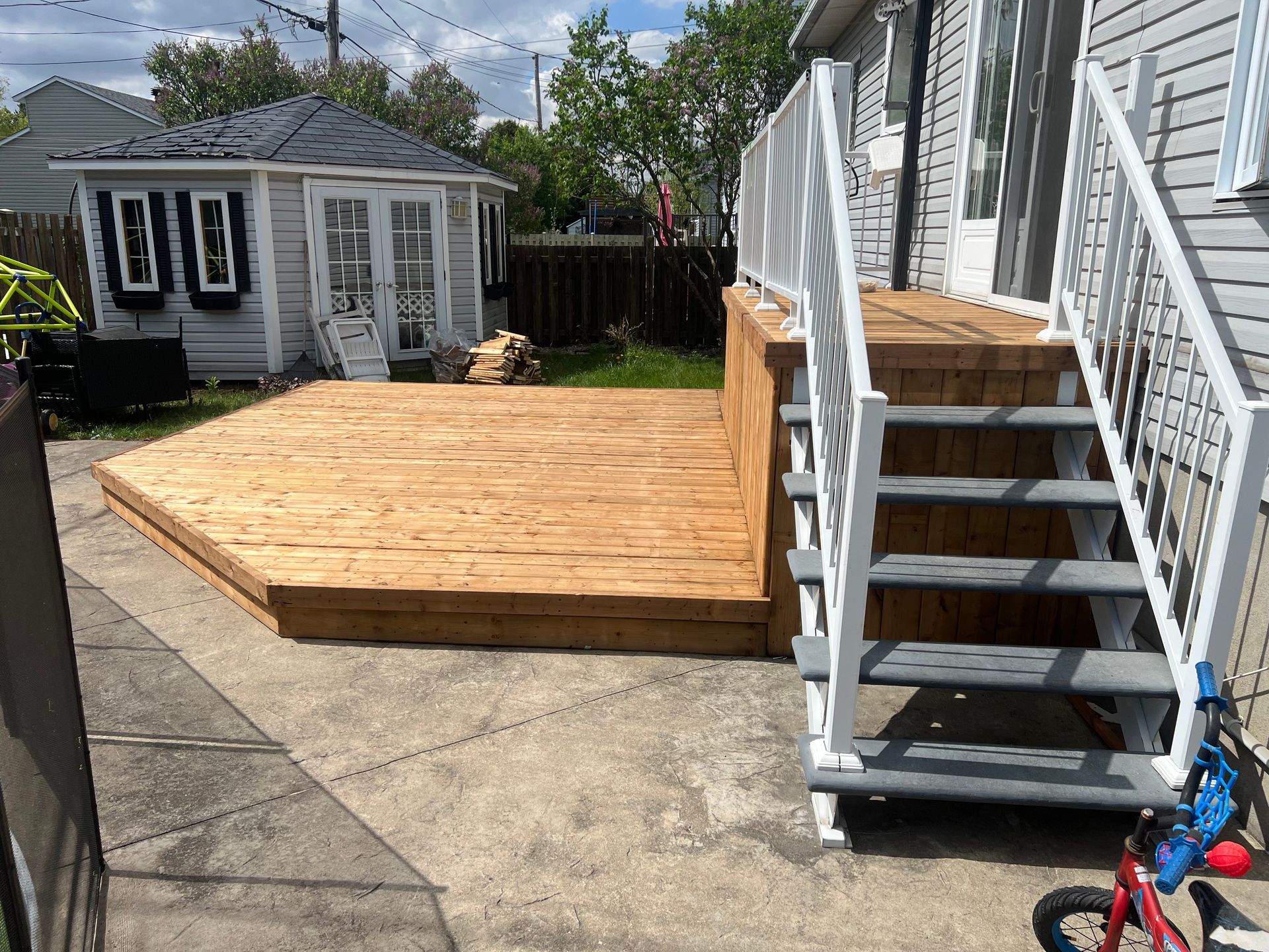 Une terrasse en bois avec des escaliers et un vélo devant une maison.