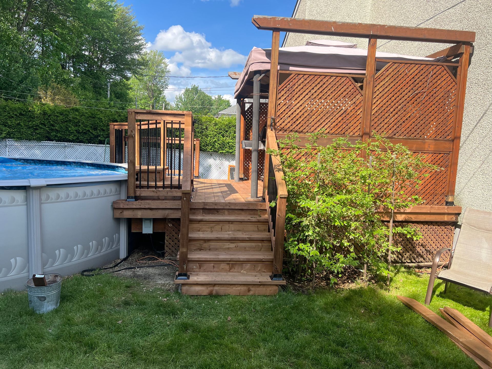 Une terrasse en bois à côté d'une piscine dans une cour arrière.