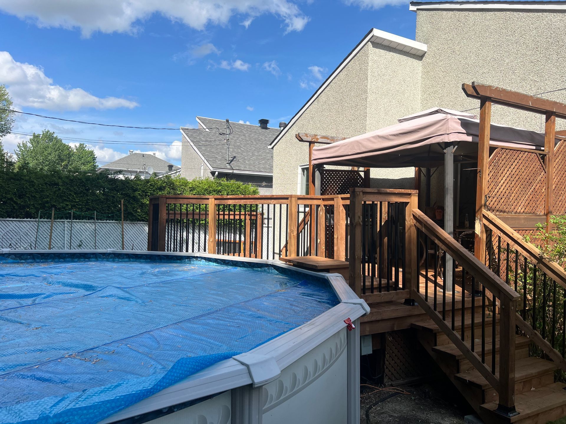Une grande piscine est entourée d'une terrasse en bois et d'escaliers.