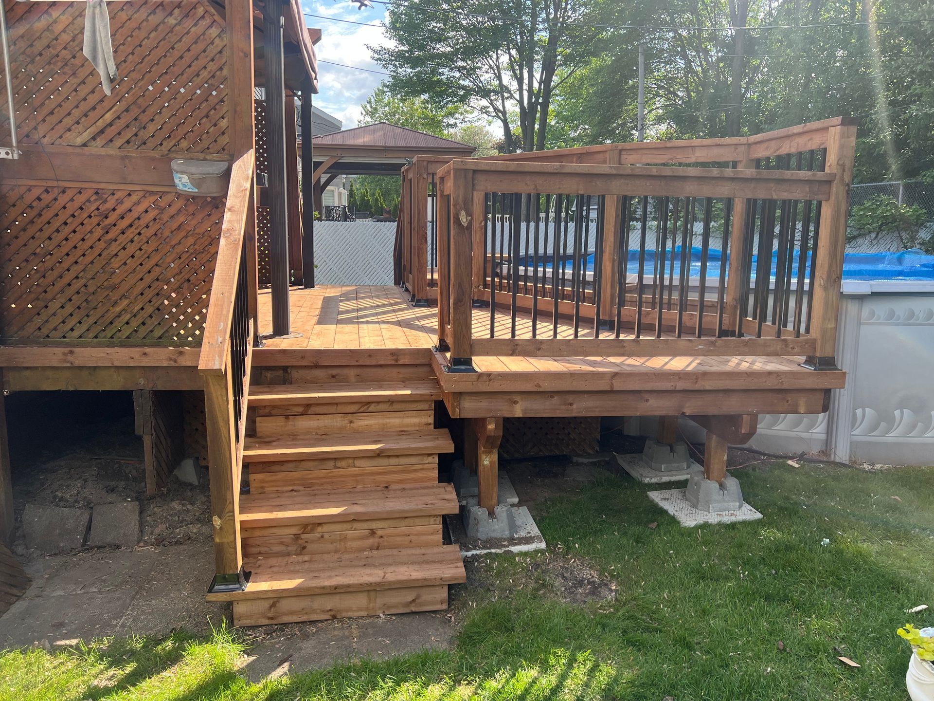Une terrasse en bois avec des escaliers et une piscine en arrière-plan.