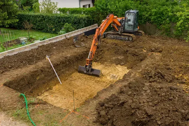 Une petite excavatrice creuse un trou dans le sol.