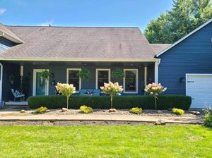 A blue house with a white garage door is sitting on top of a lush green lawn.