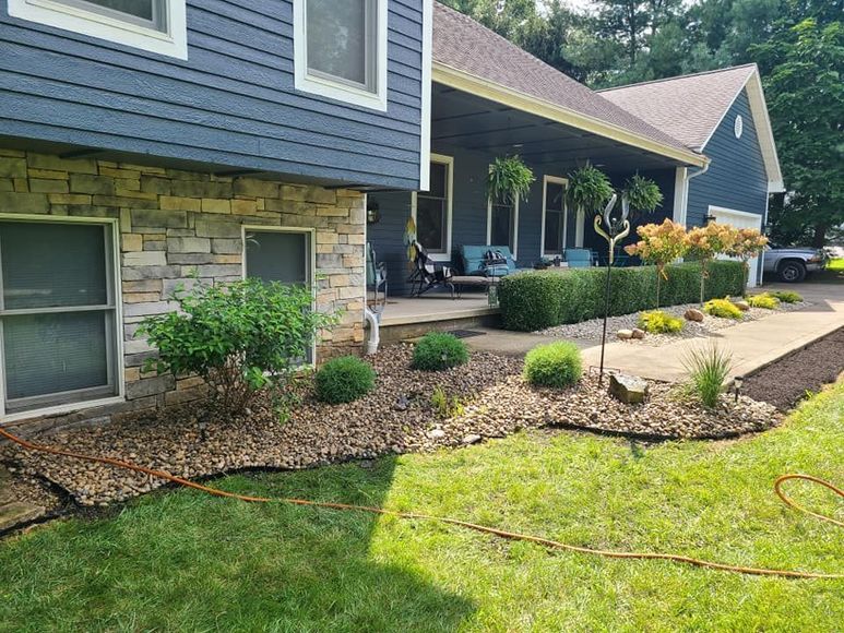 A blue house with a stone facade and a lush green lawn in front of it.