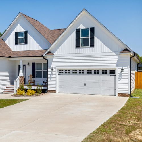 A white house with a brown roof and black shutters
