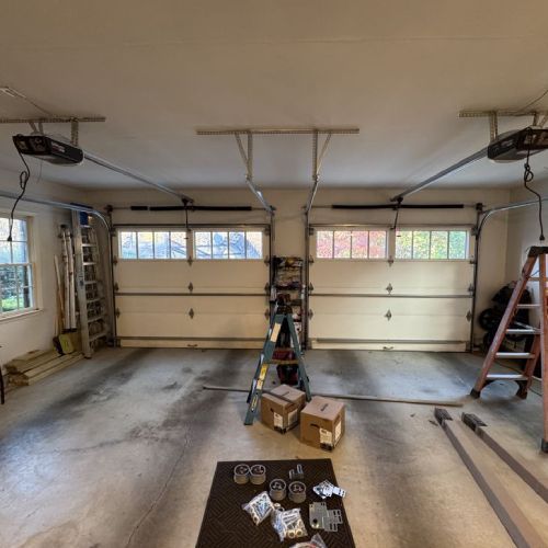 A garage with two garage doors open and boxes on the floor.