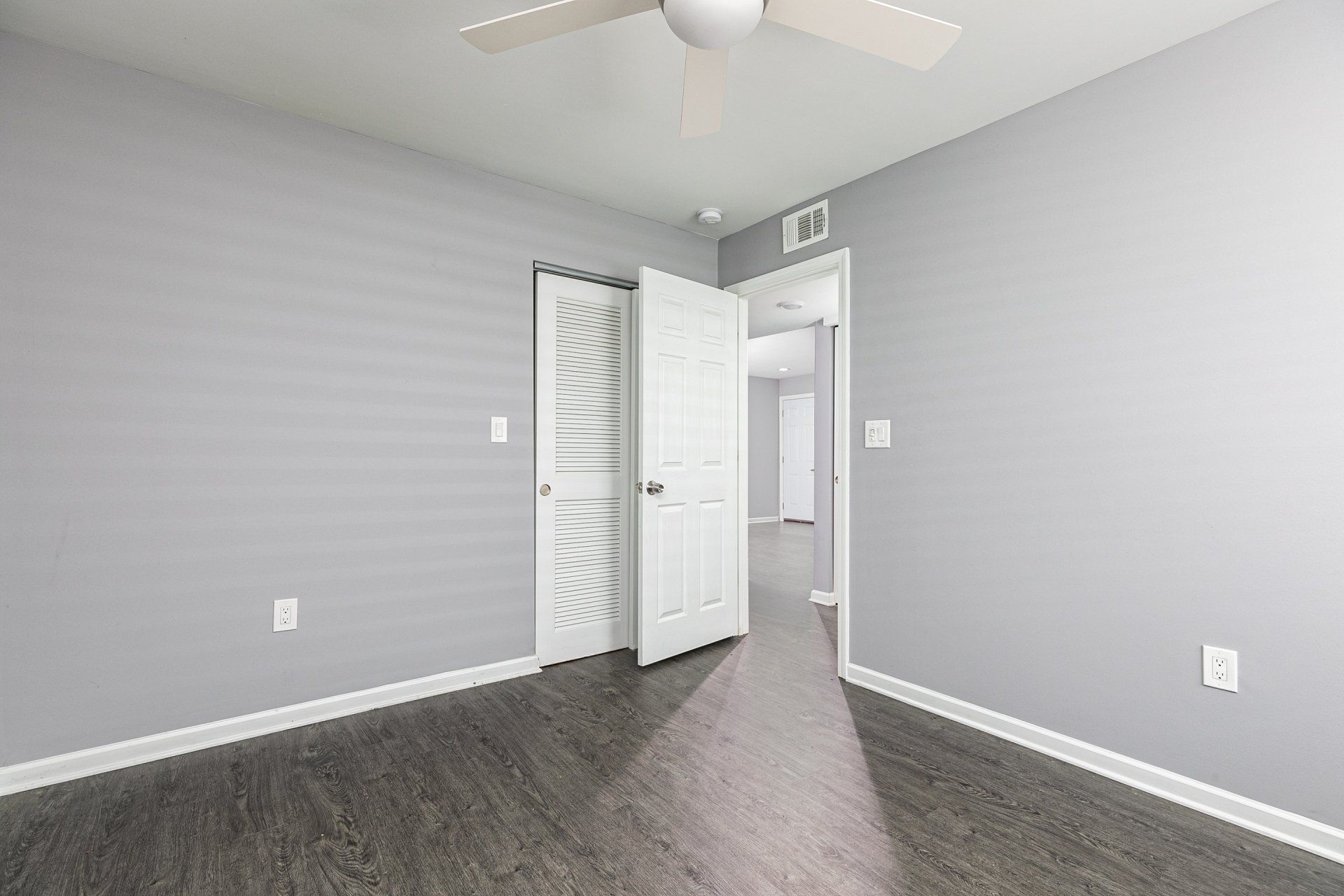 Dog-Friendly Apartments In Forest Park, GA - Gardens at Park West - Spacious Bedroom With Vinyl Plank Flooring, Ceiling Fan, And Closet.
