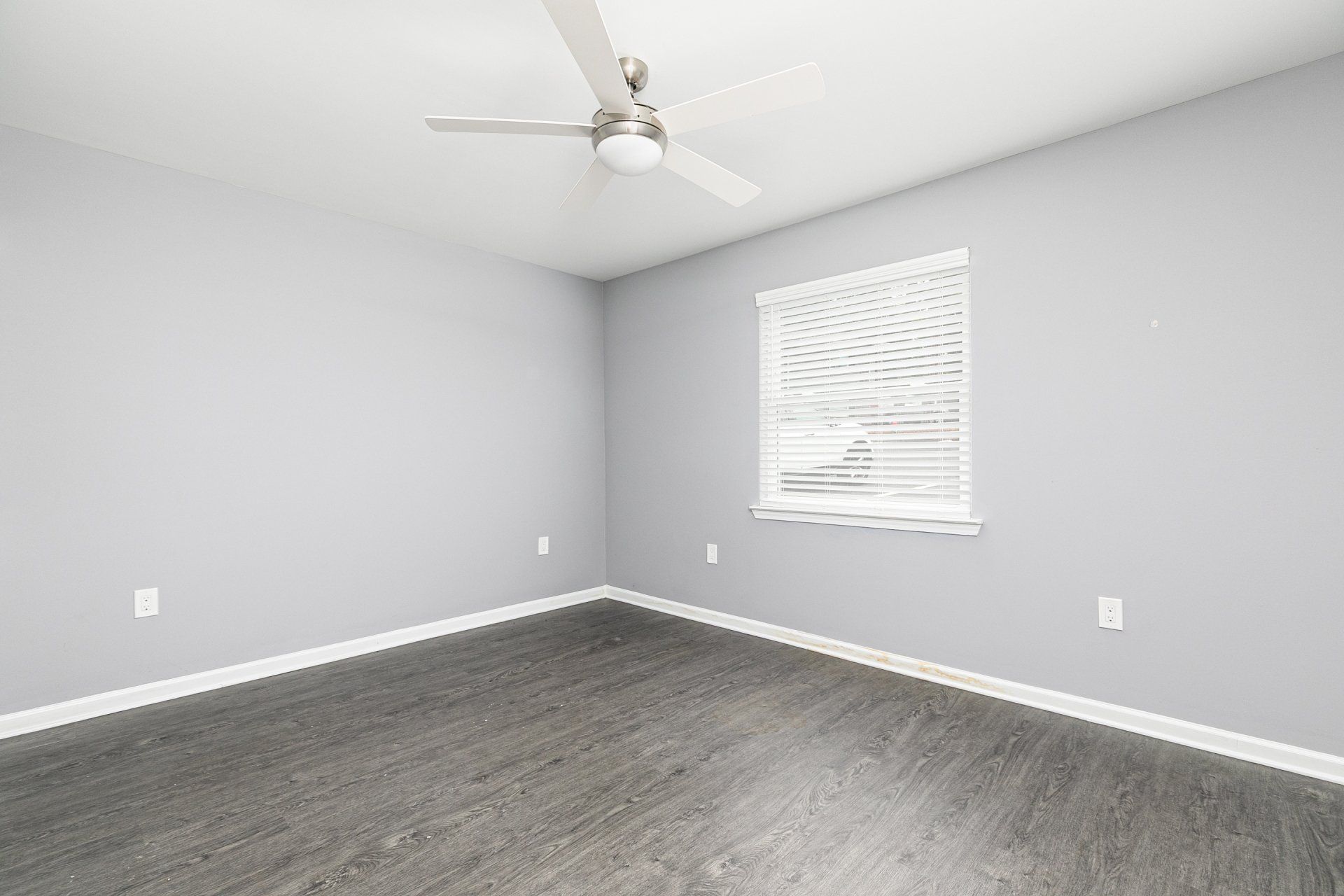 1-Bedroom Apartments in Forest Park, GA - Gardens at Park West - Unfurnished Bedroom with Vinyl Plank Flooring, Soft Grey Walls, Ceiling Fan, and Window with Blinds