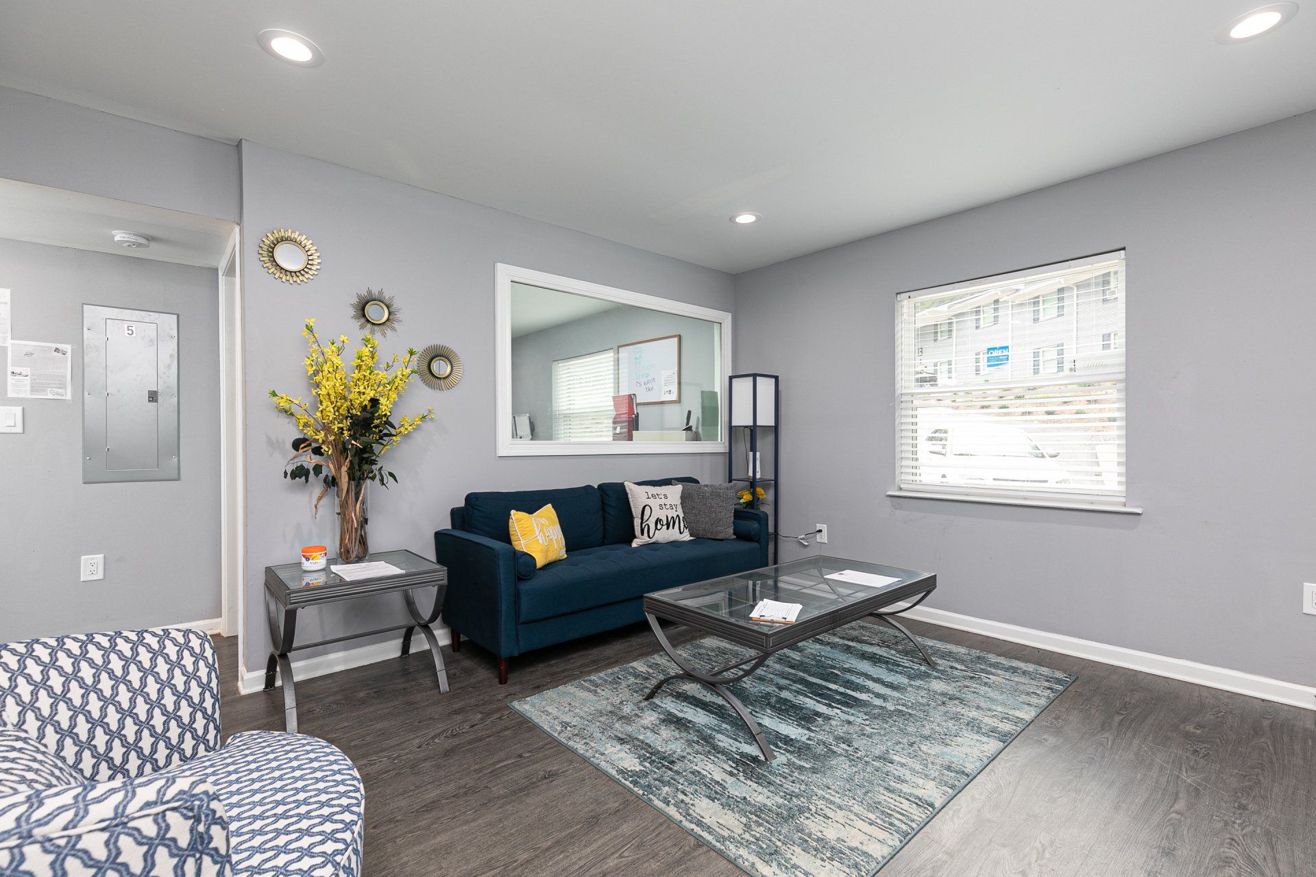 One-Bedroom Apartments In Forest Park, GA - Gardens at Park West - Cozy Living Room With Vinyl Plank Flooring, Sofa, End Table, Coffee Table, Armchair, Recessed Lighting, And Window.