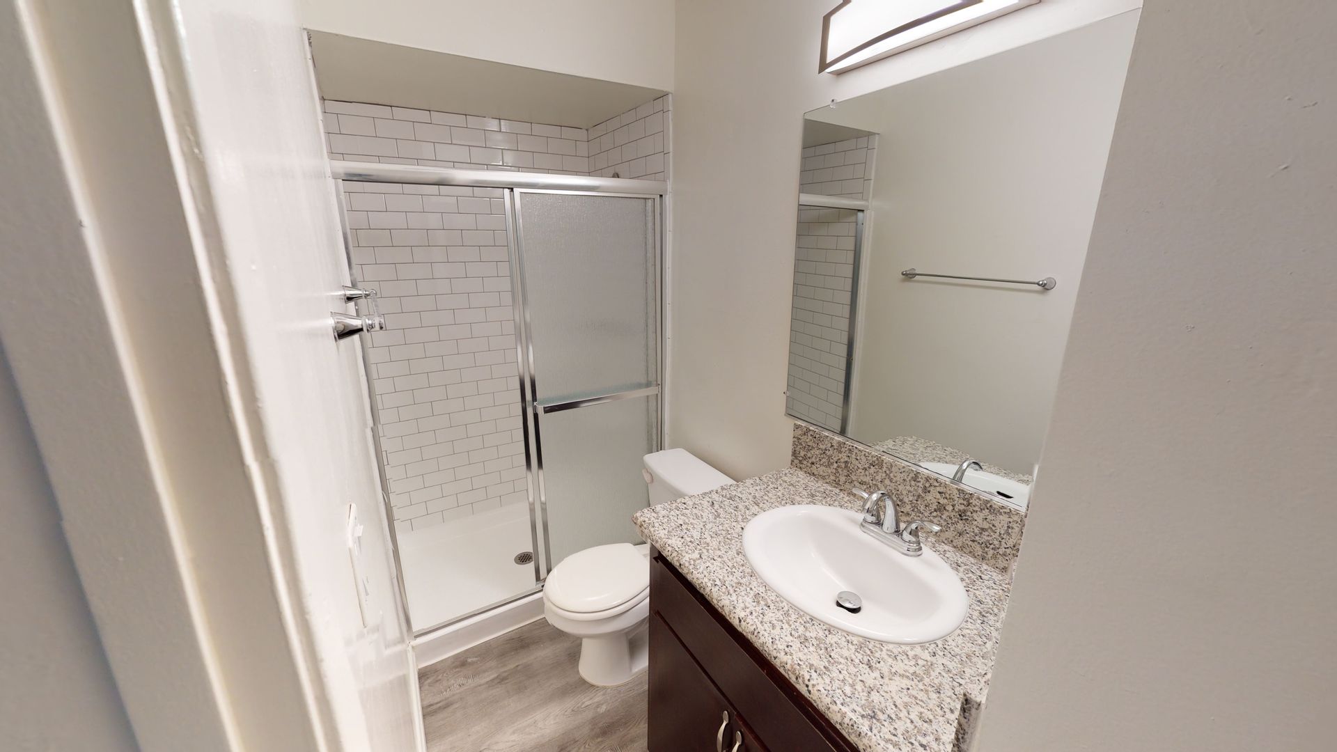 Bathroom with shower, toilet, vanity, and mirror. White and gray tones, modern design.