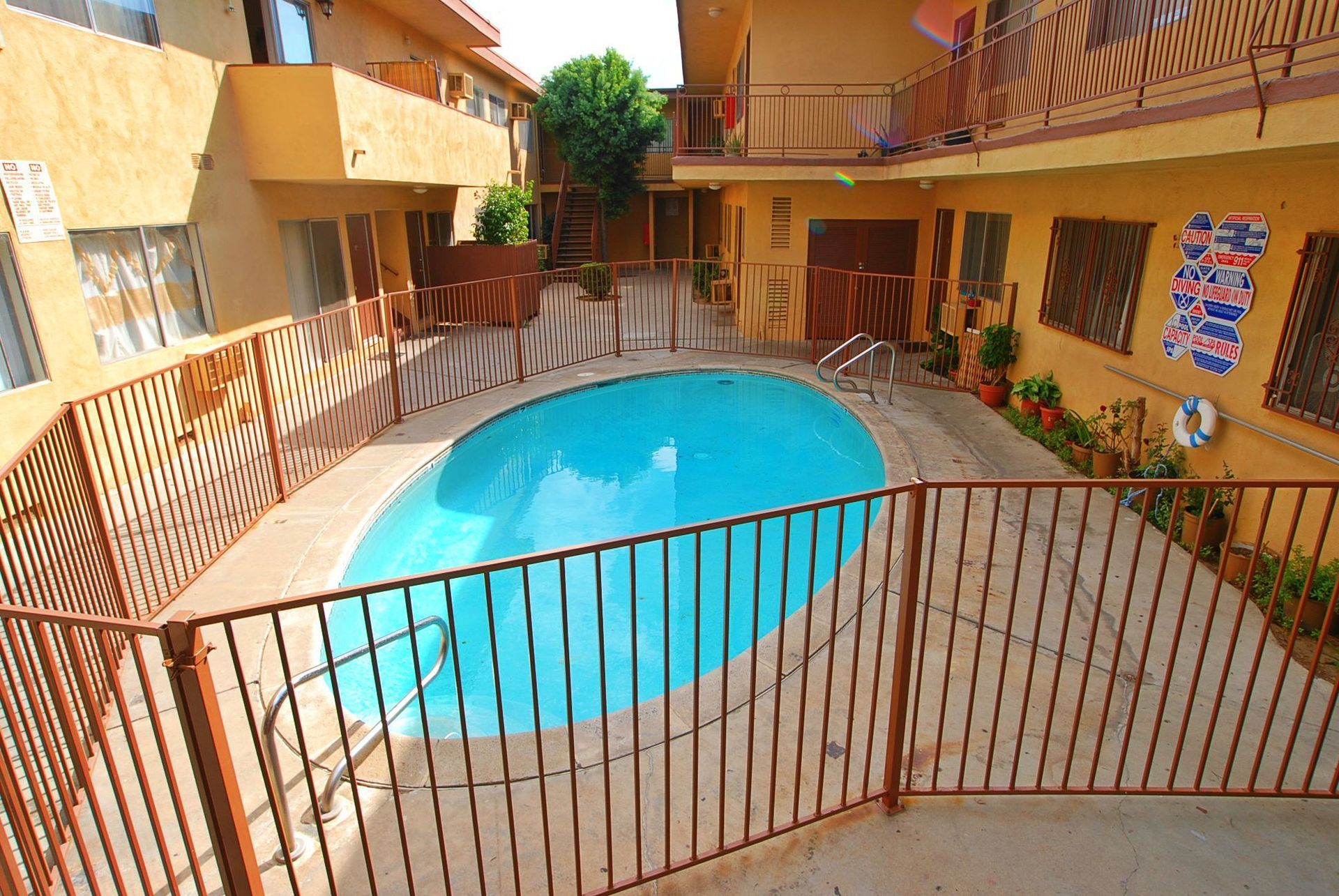 Courtyard with a pool, brown fence, and tan apartment buildings.