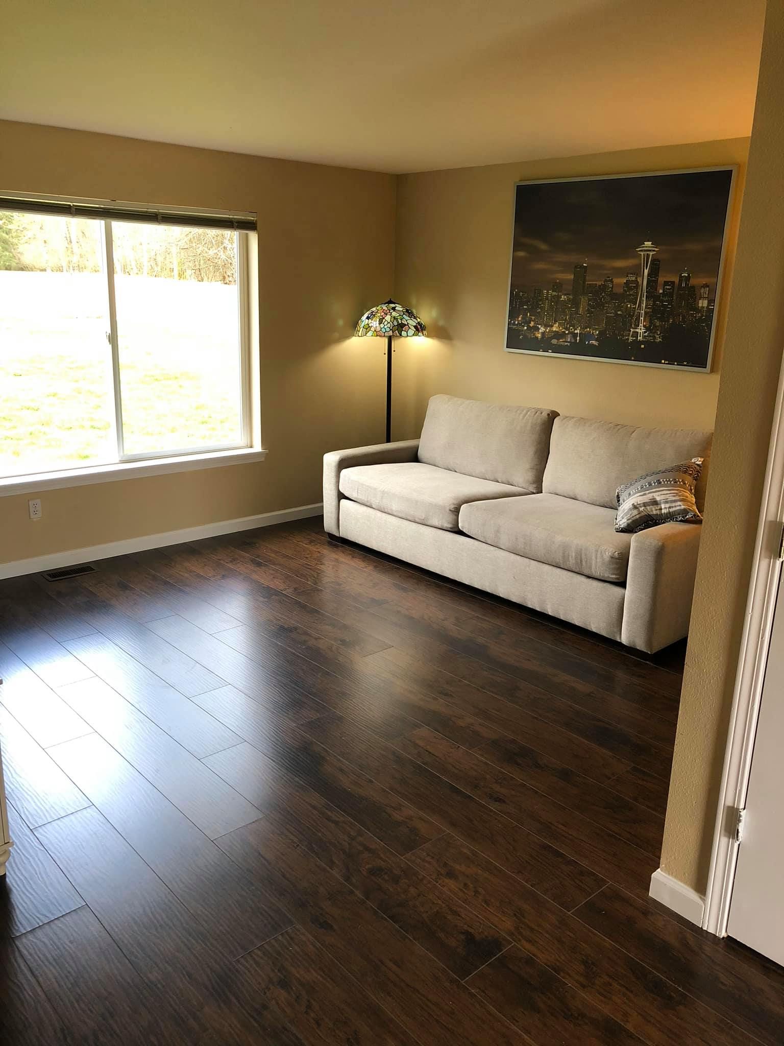 A living room with a couch , lamp , and large window.