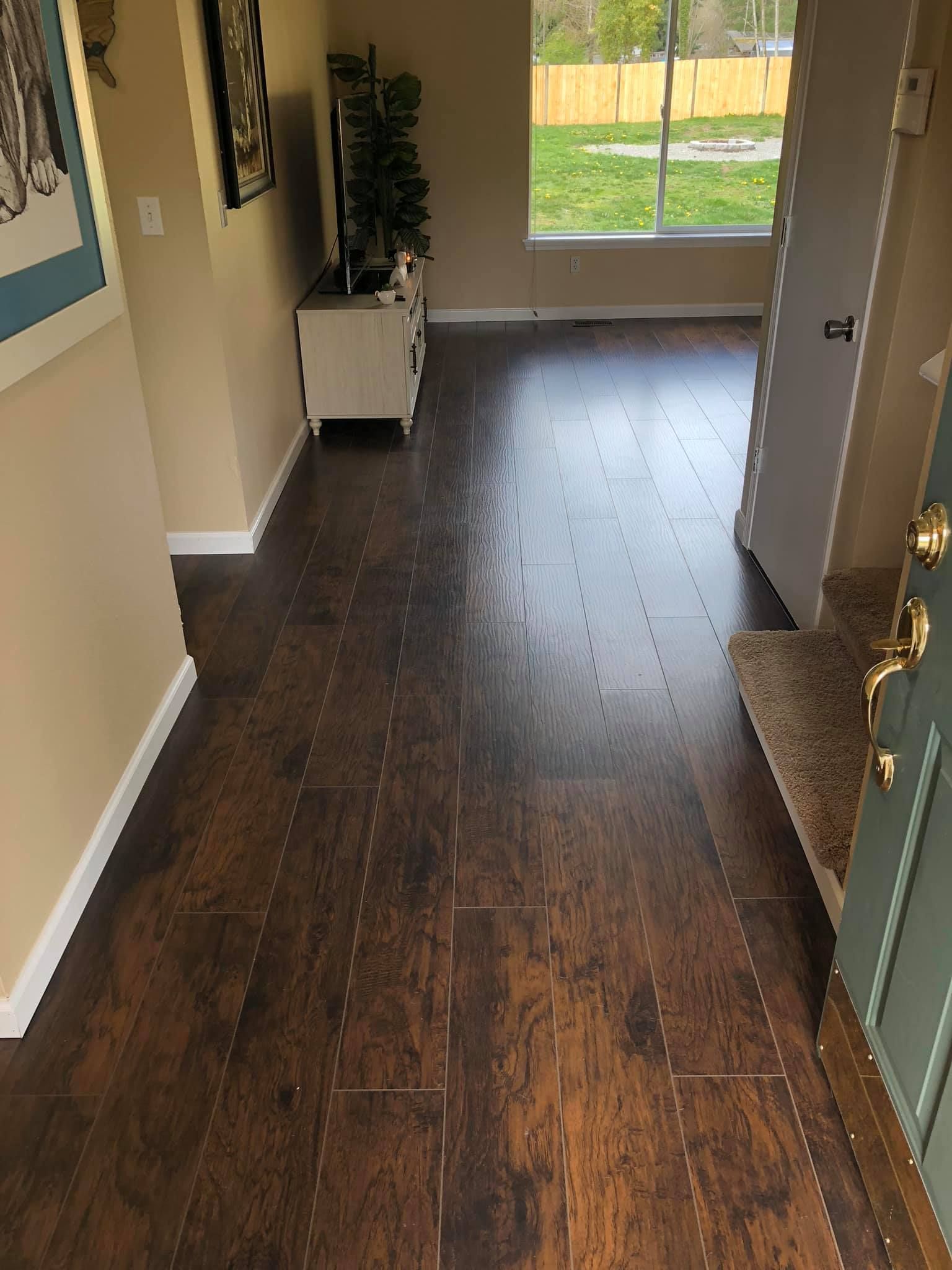 A hallway with a wooden floor and stairs in a house.