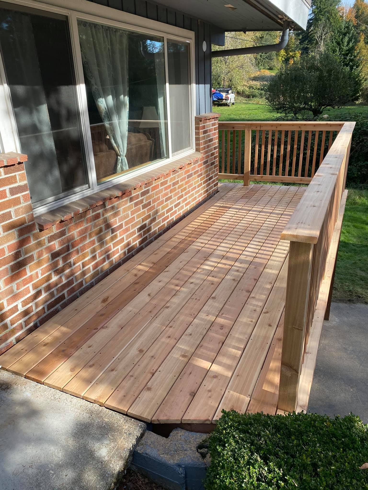 A wooden deck is sitting in front of a brick house.