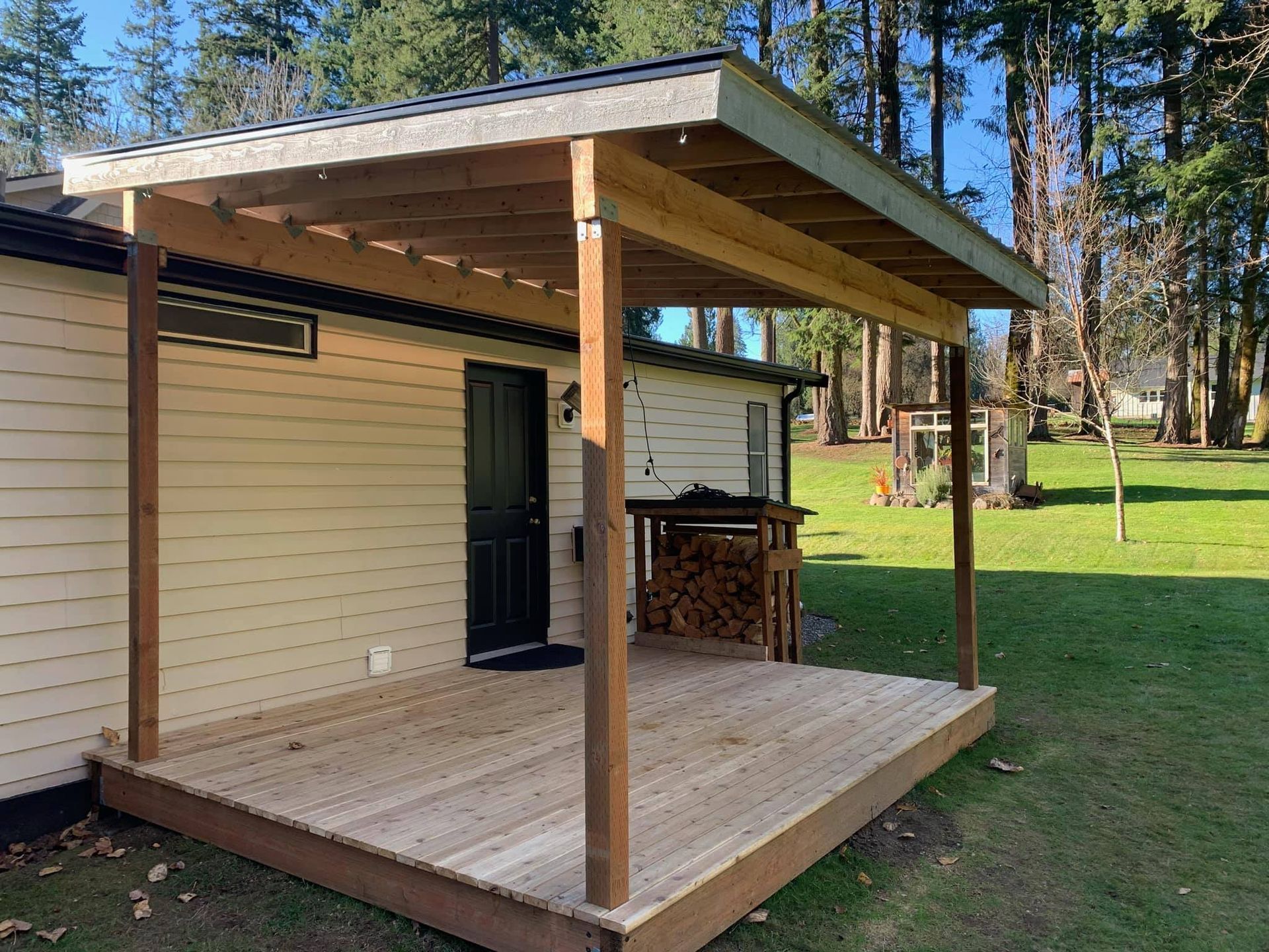 A wooden deck with a roof over it is in front of a house.