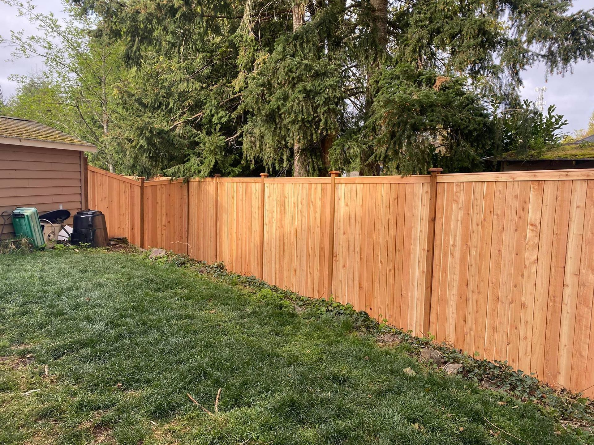 A wooden fence is in the backyard of a house.