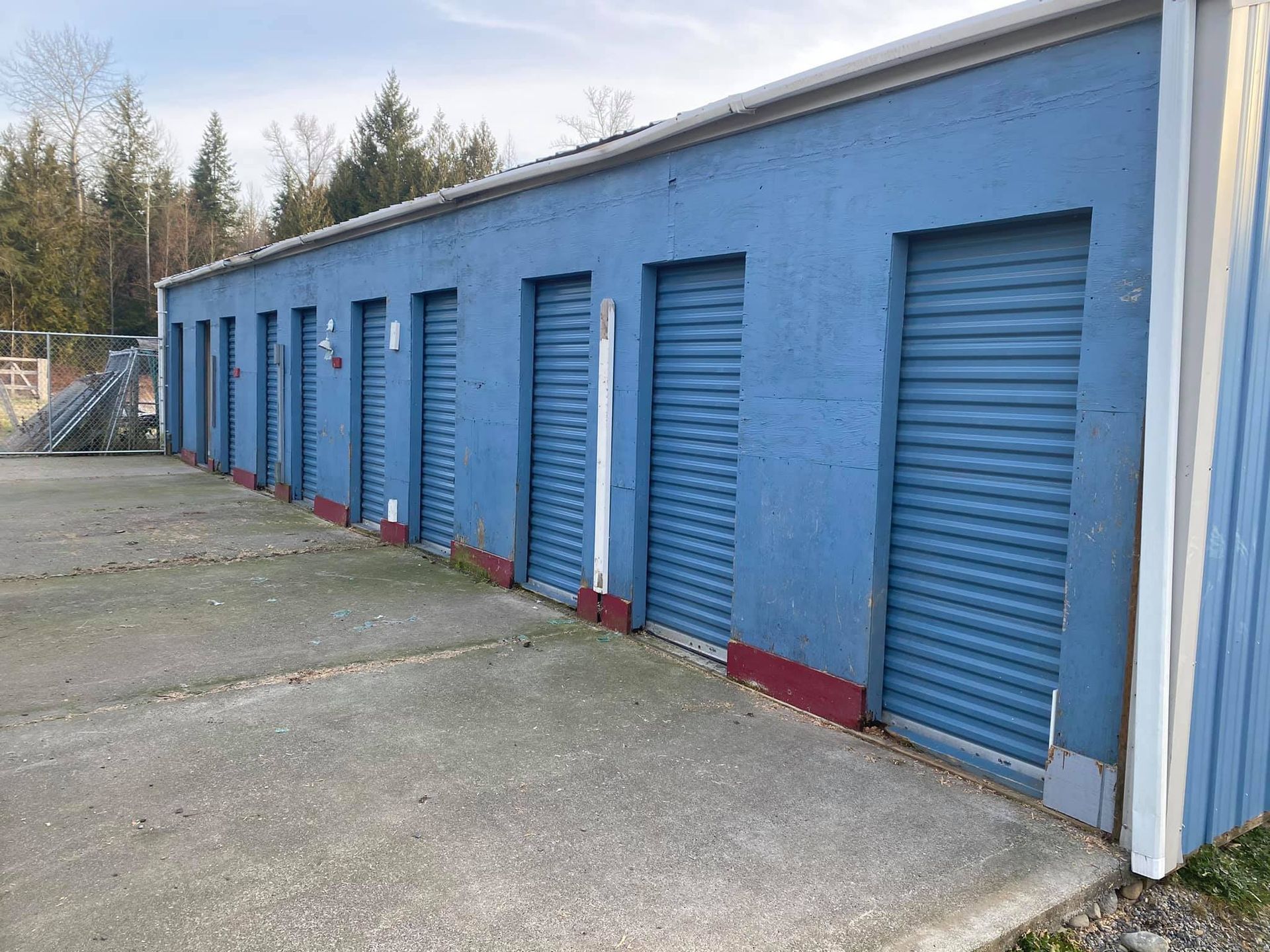 A row of blue garage doors are lined up in a parking lot.