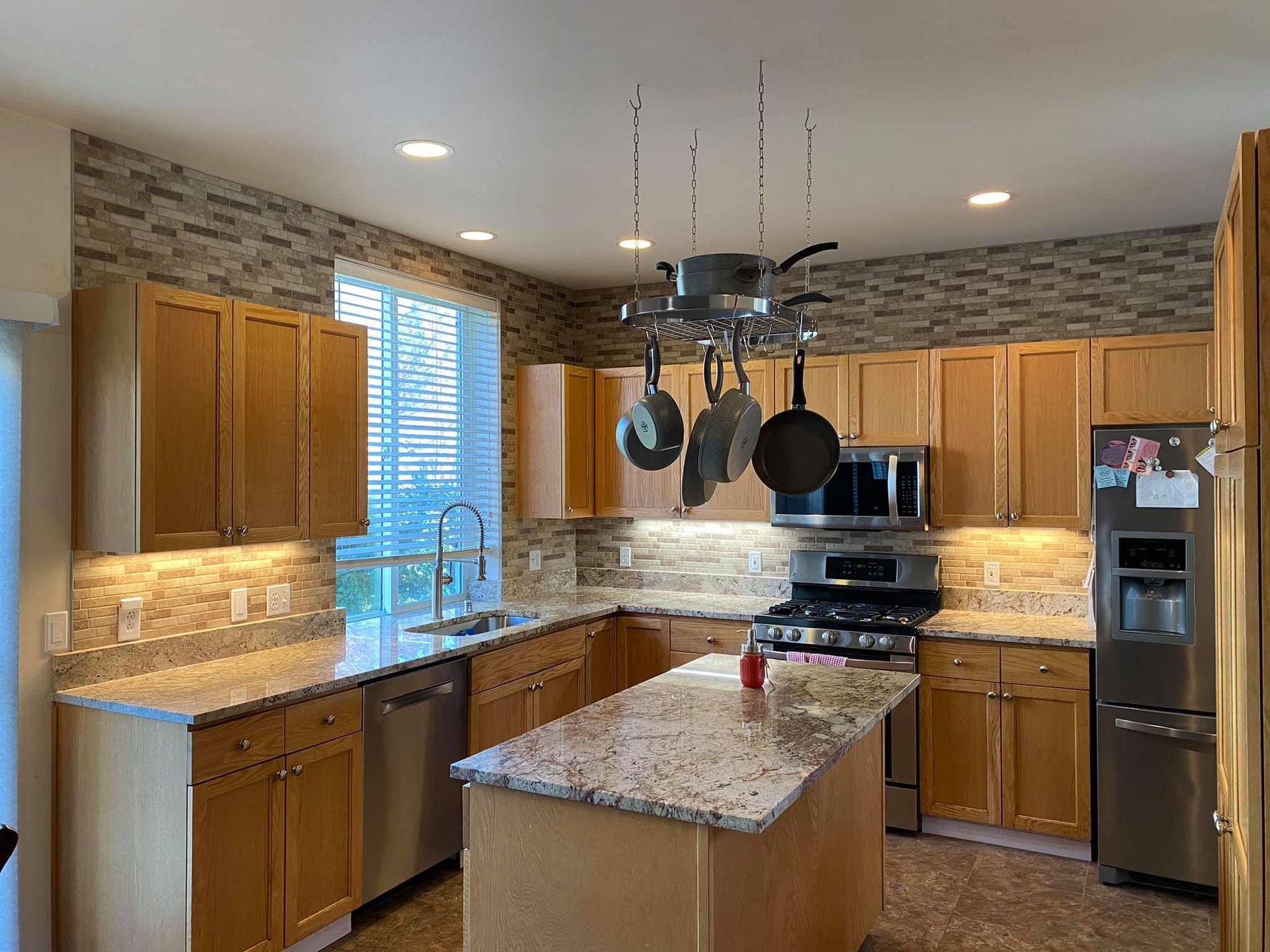 A kitchen with wooden cabinets , granite counter tops , stainless steel appliances , and a large island.