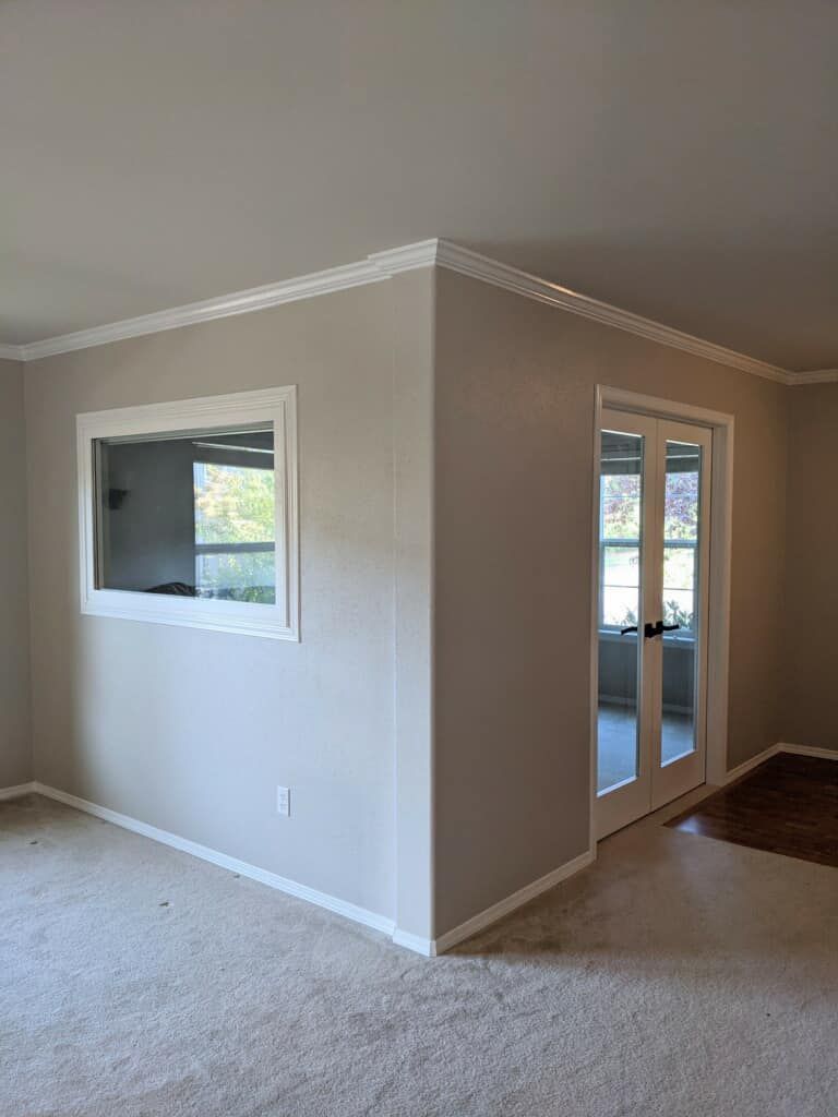 A living room with a large window and sliding glass doors.