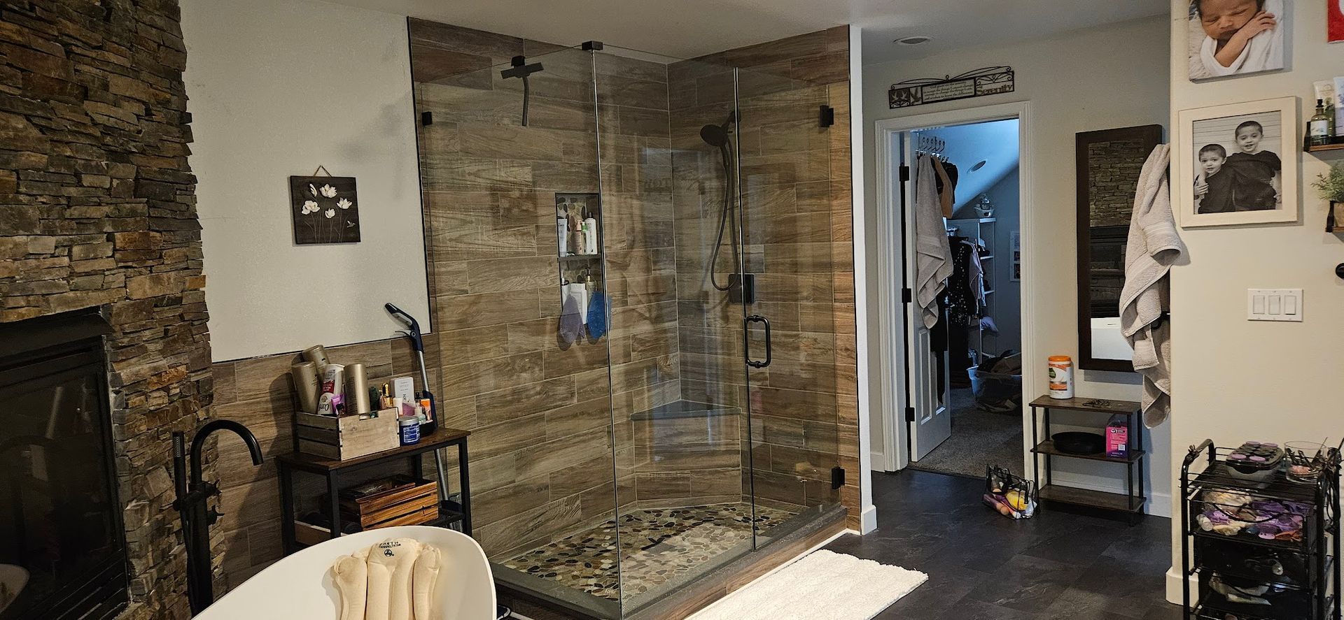 A bathroom with a walk in shower , tub and fireplace.