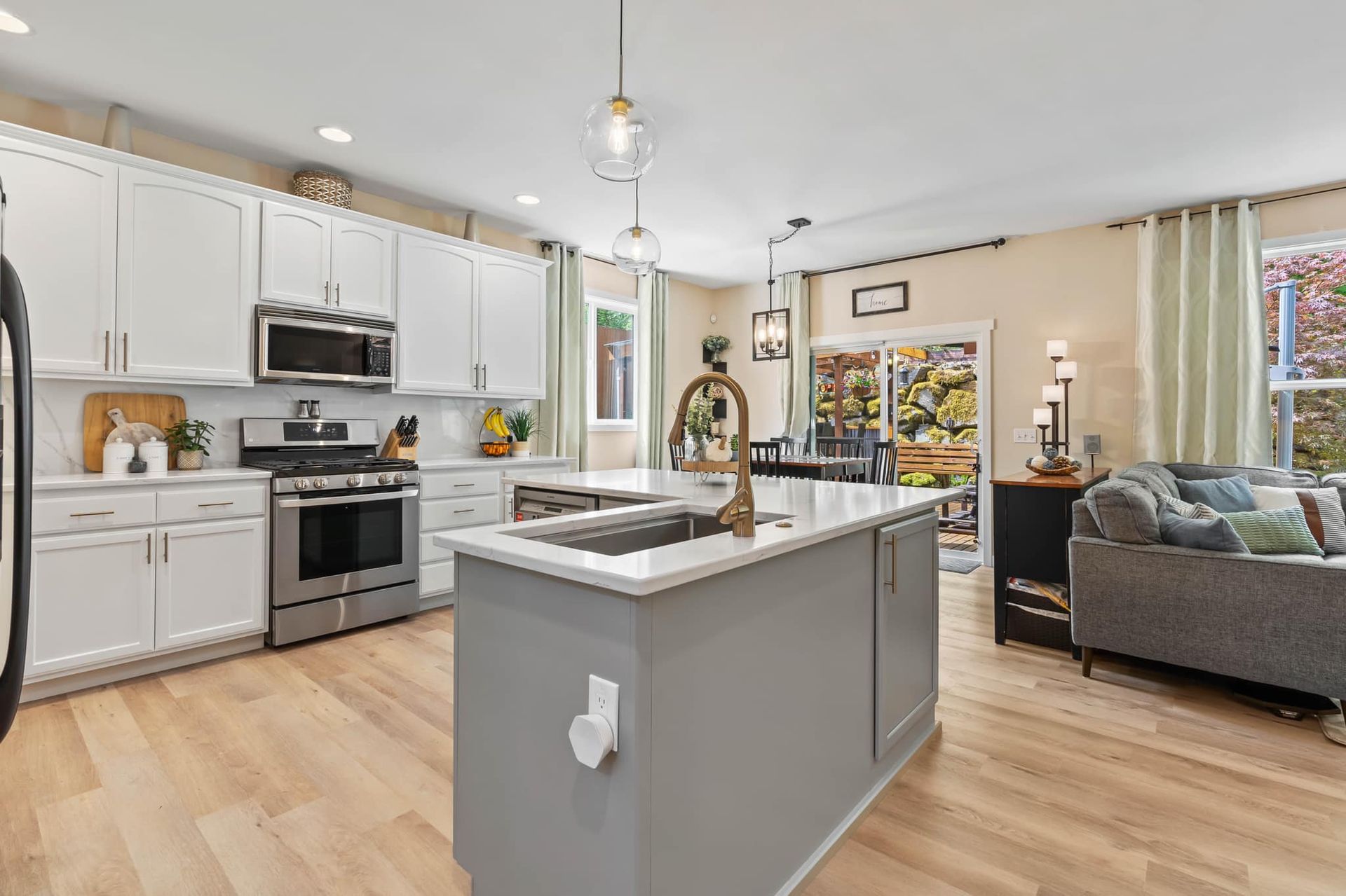 A kitchen with white cabinets , stainless steel appliances , a sink , and a large island.