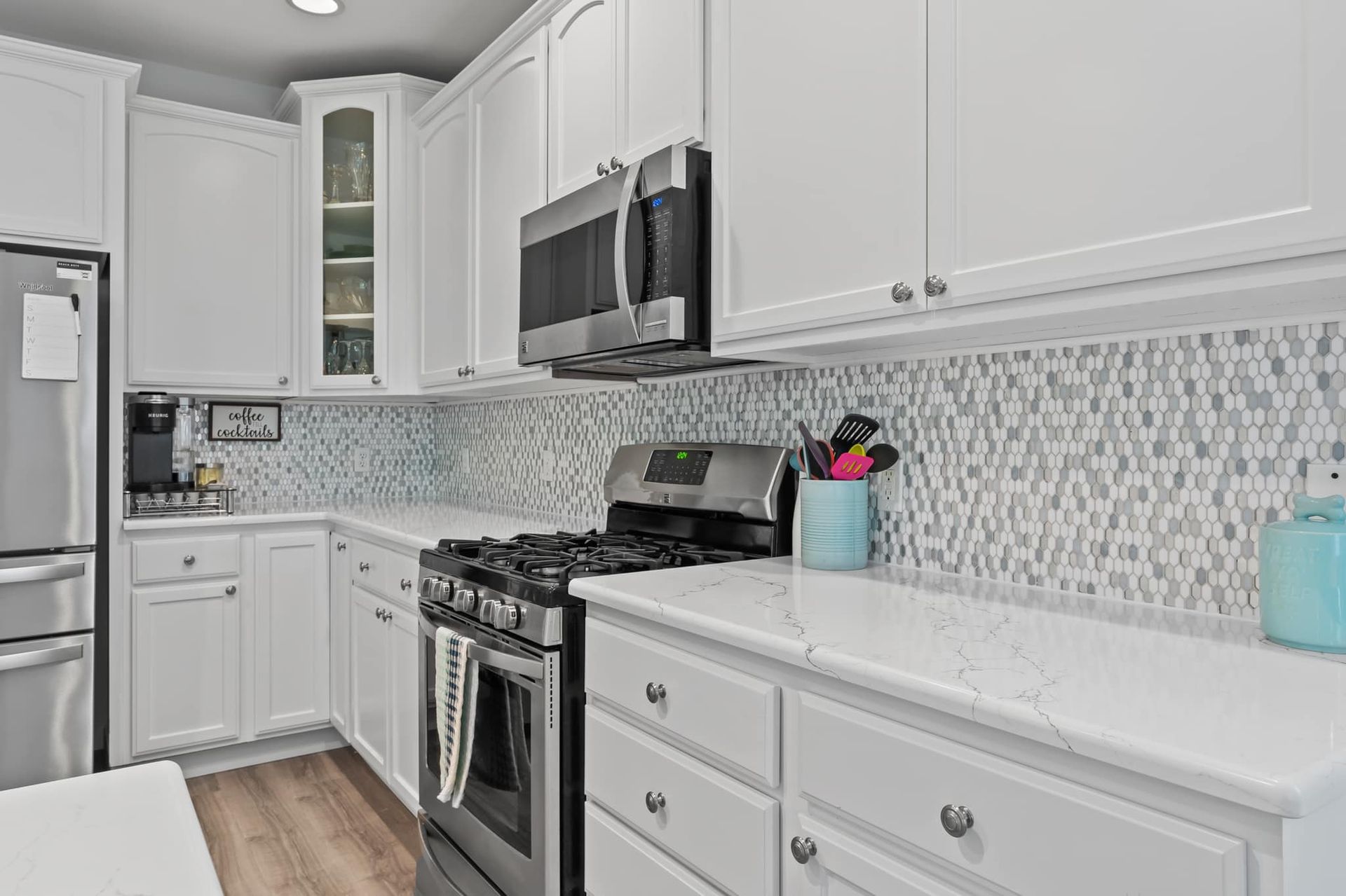 A kitchen with white cabinets , stainless steel appliances , and a stove.