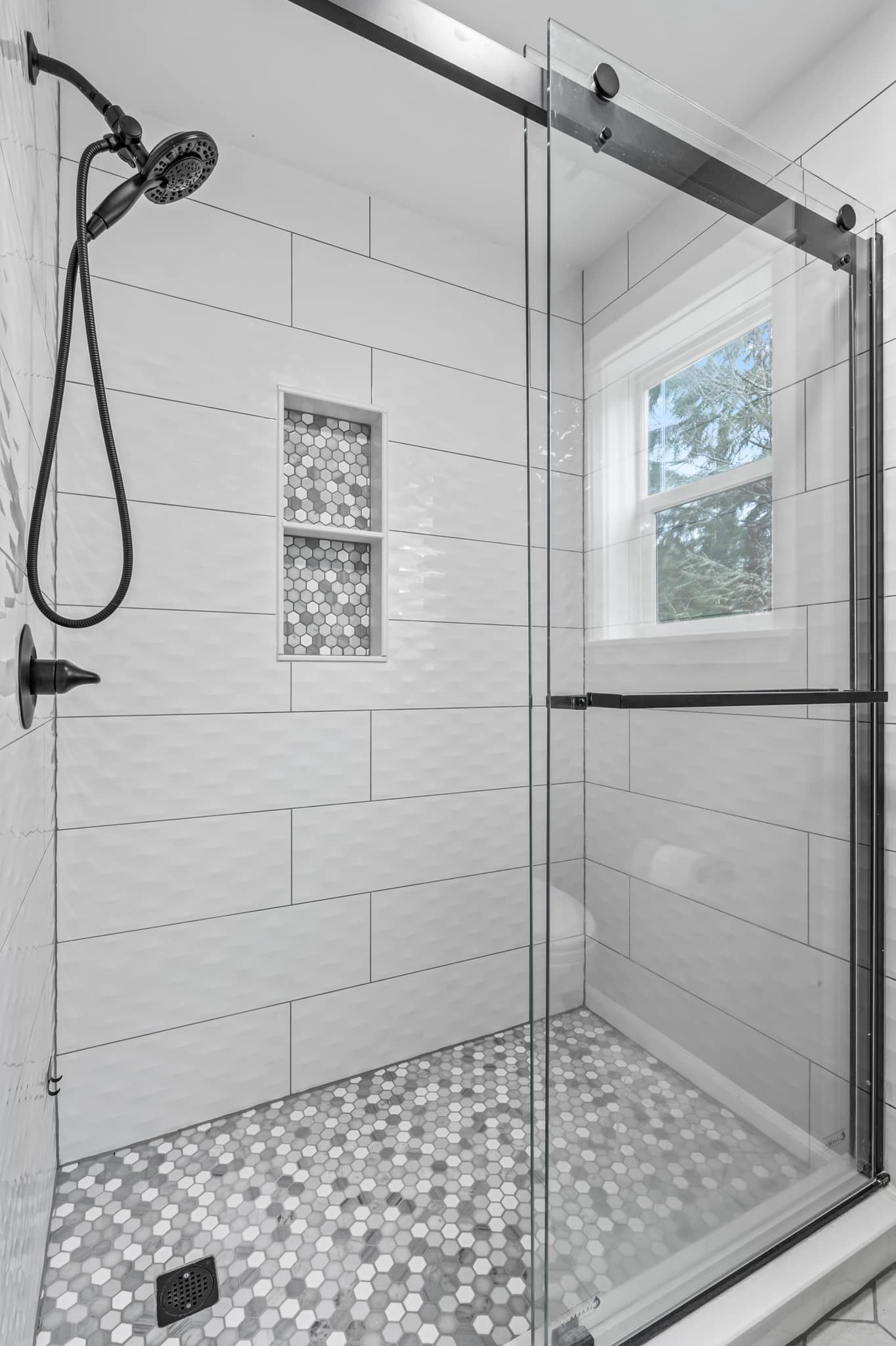 A shower with a sliding glass door and a window.