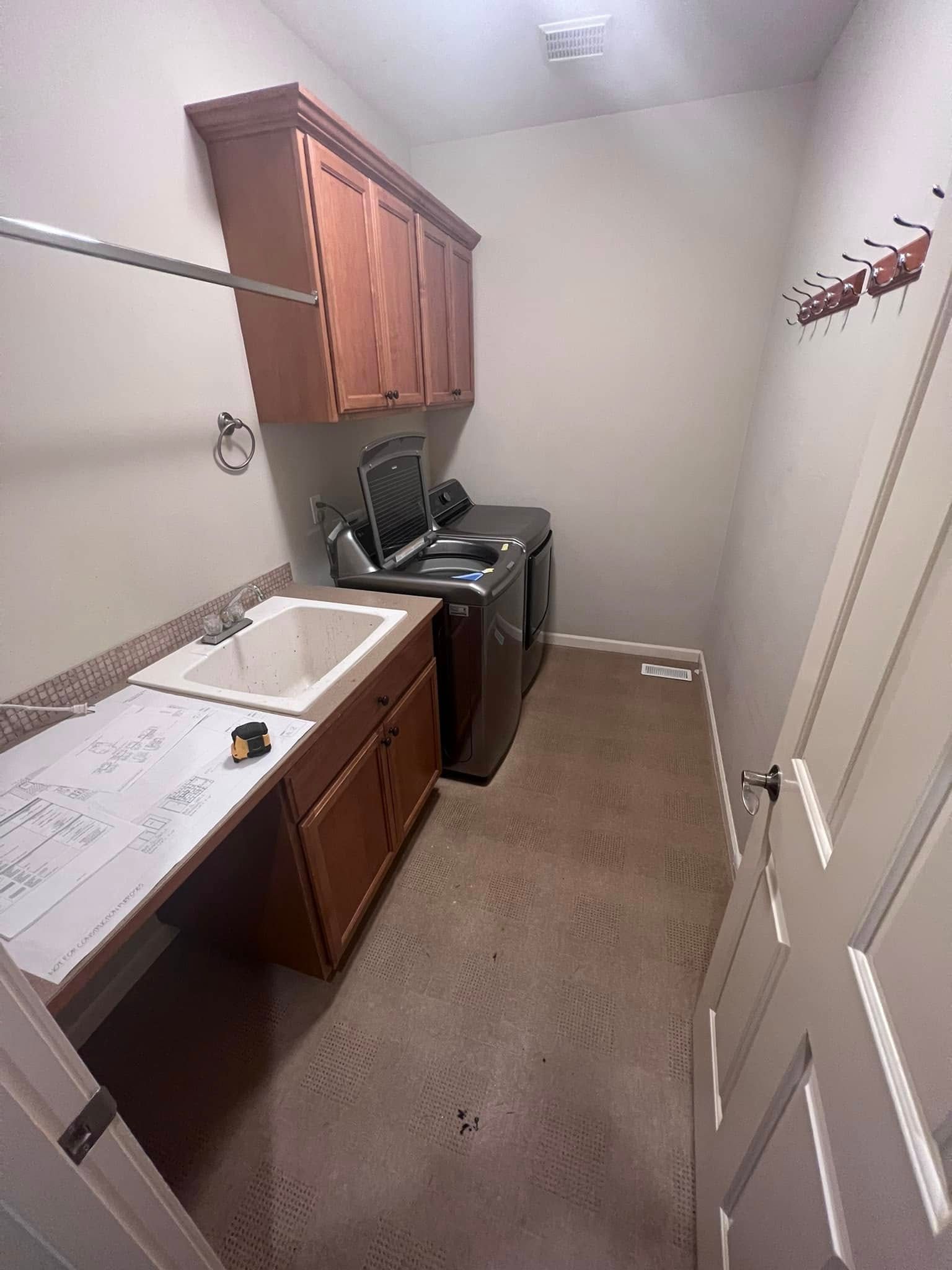 A laundry room with a sink , washer and dryer , and cabinets.