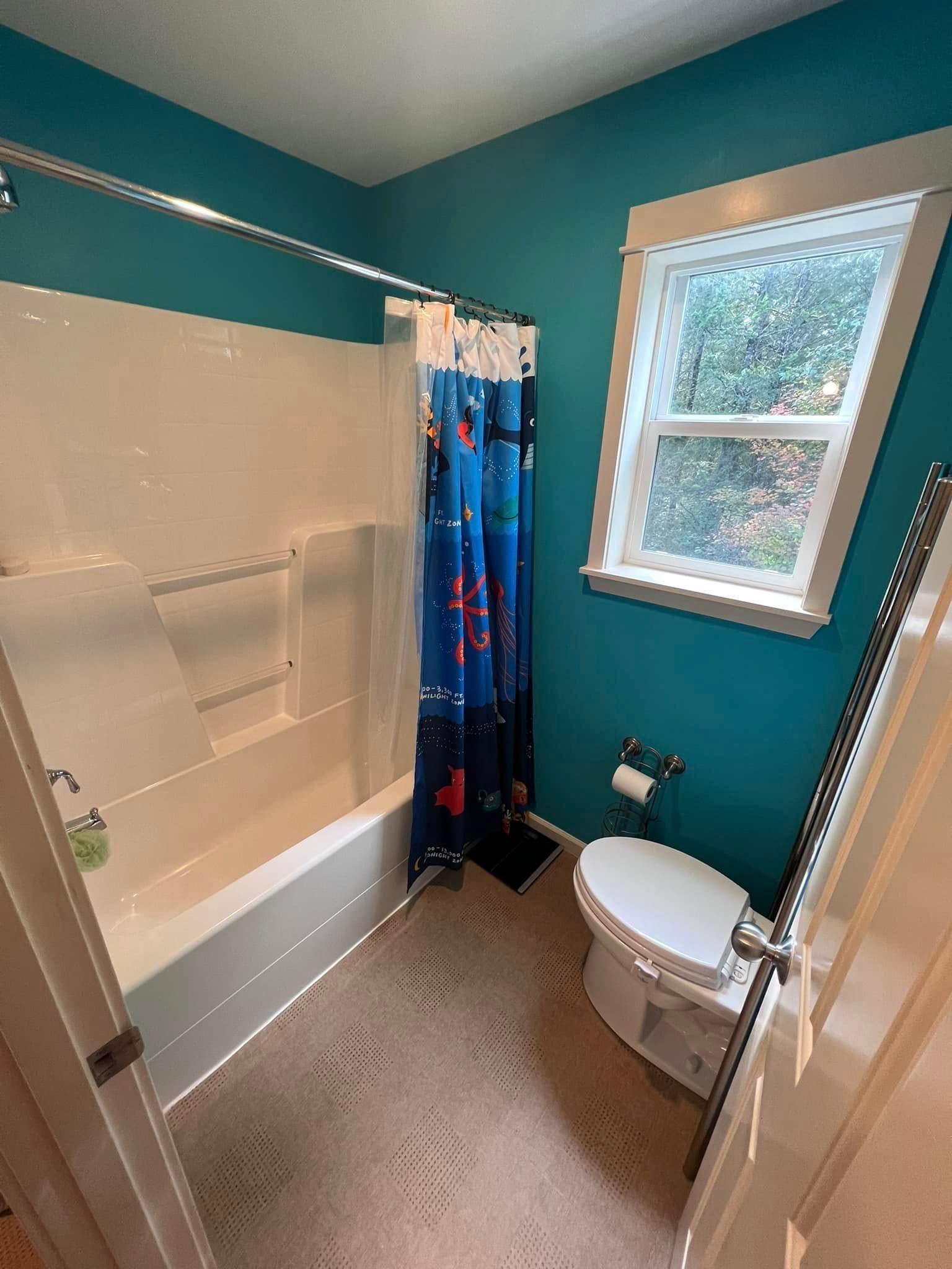 A bathroom with a tub , toilet , shower and window.