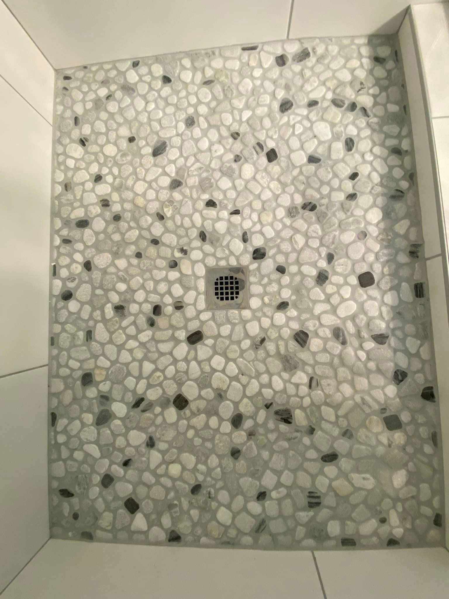 A shower stall with a tiled floor and a drain.