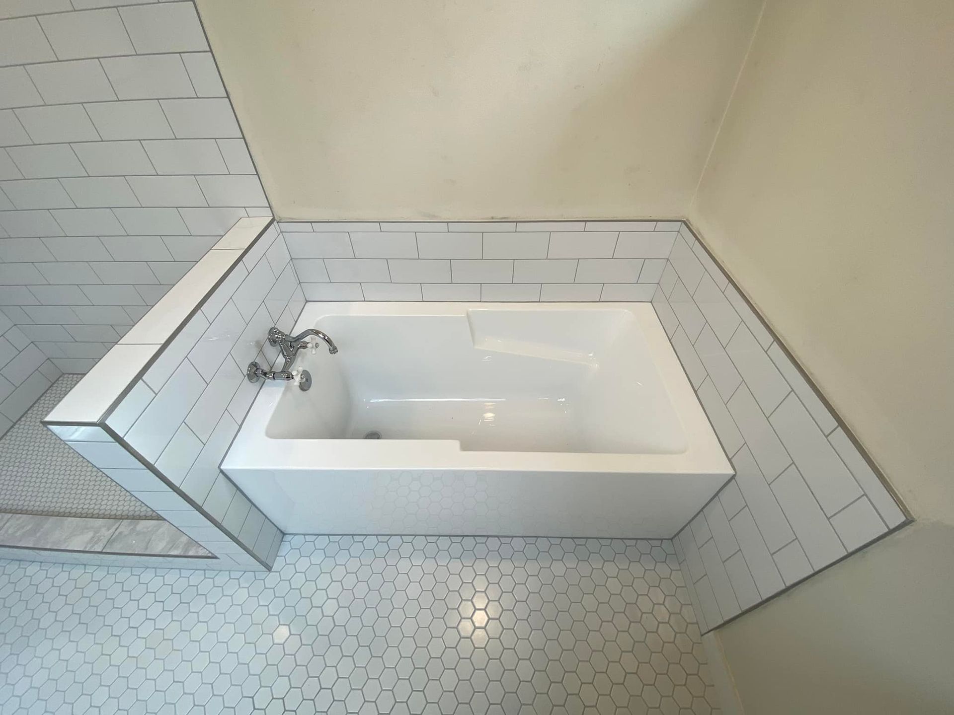 A bathtub in a bathroom surrounded by white tiles