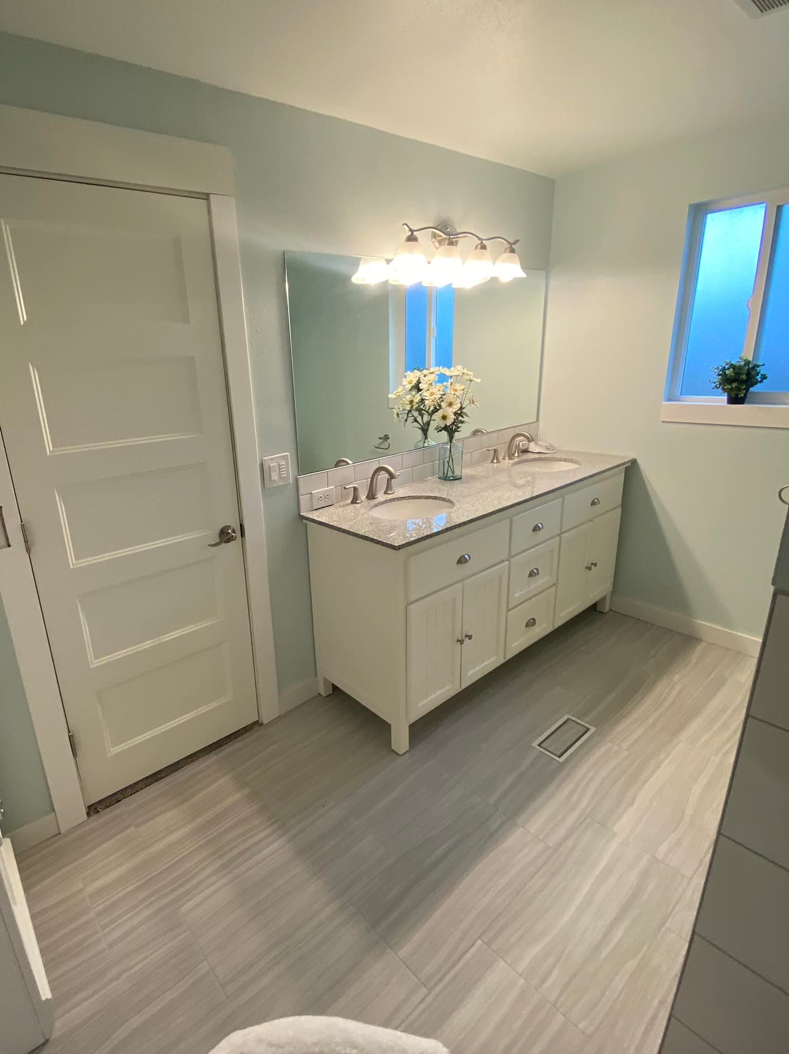 A bathroom with two sinks , a mirror and a window.