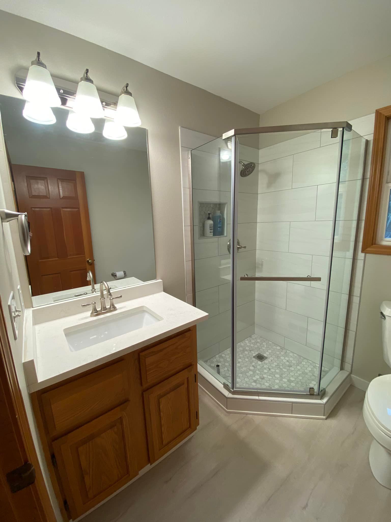 A bathroom with a sink , toilet , shower and mirror.