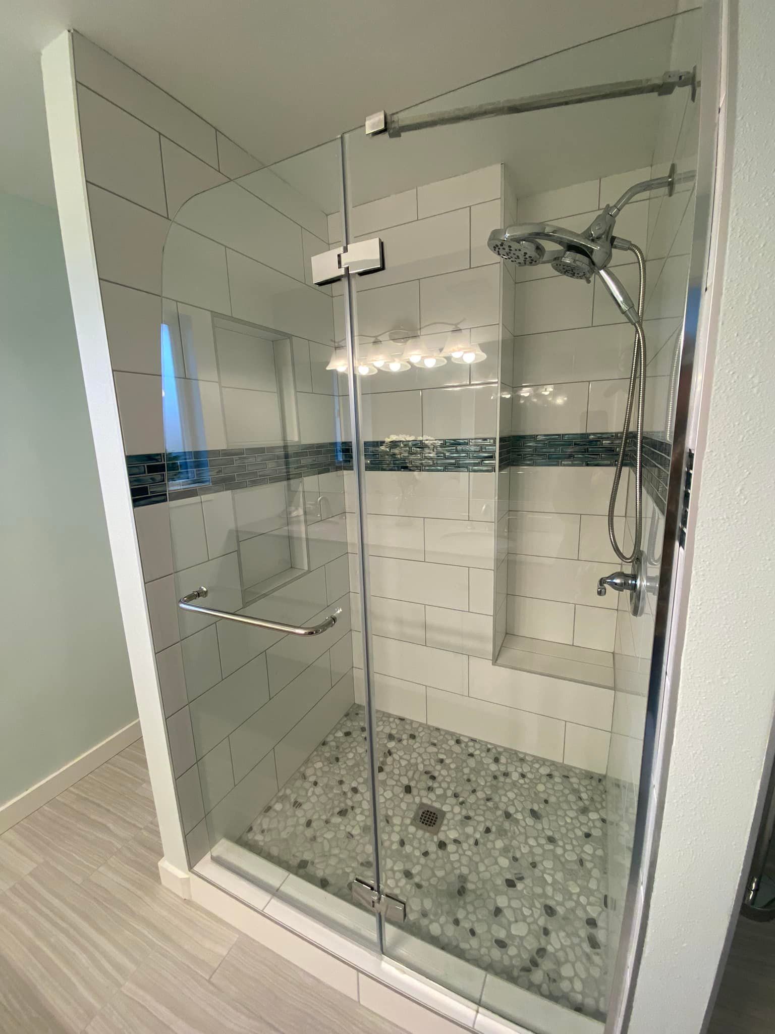 A bathroom with a walk in shower with a glass door and a shower head.